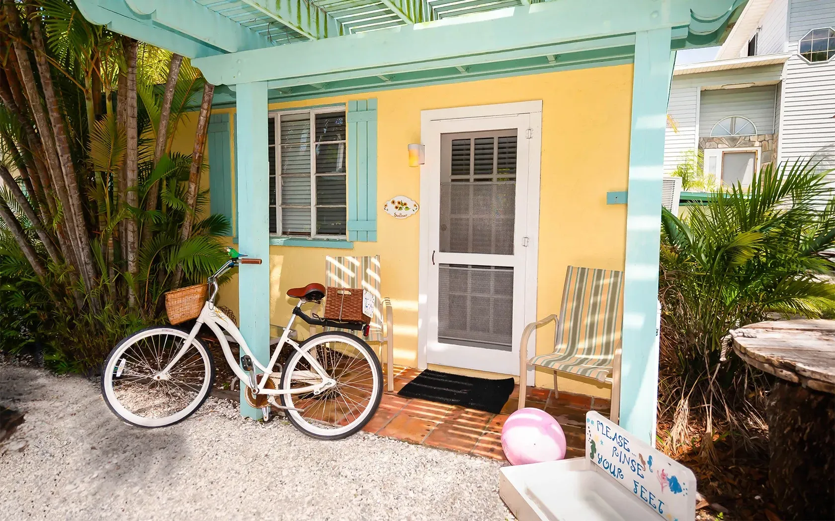 A bicycle is parked on the porch of a yellow house.