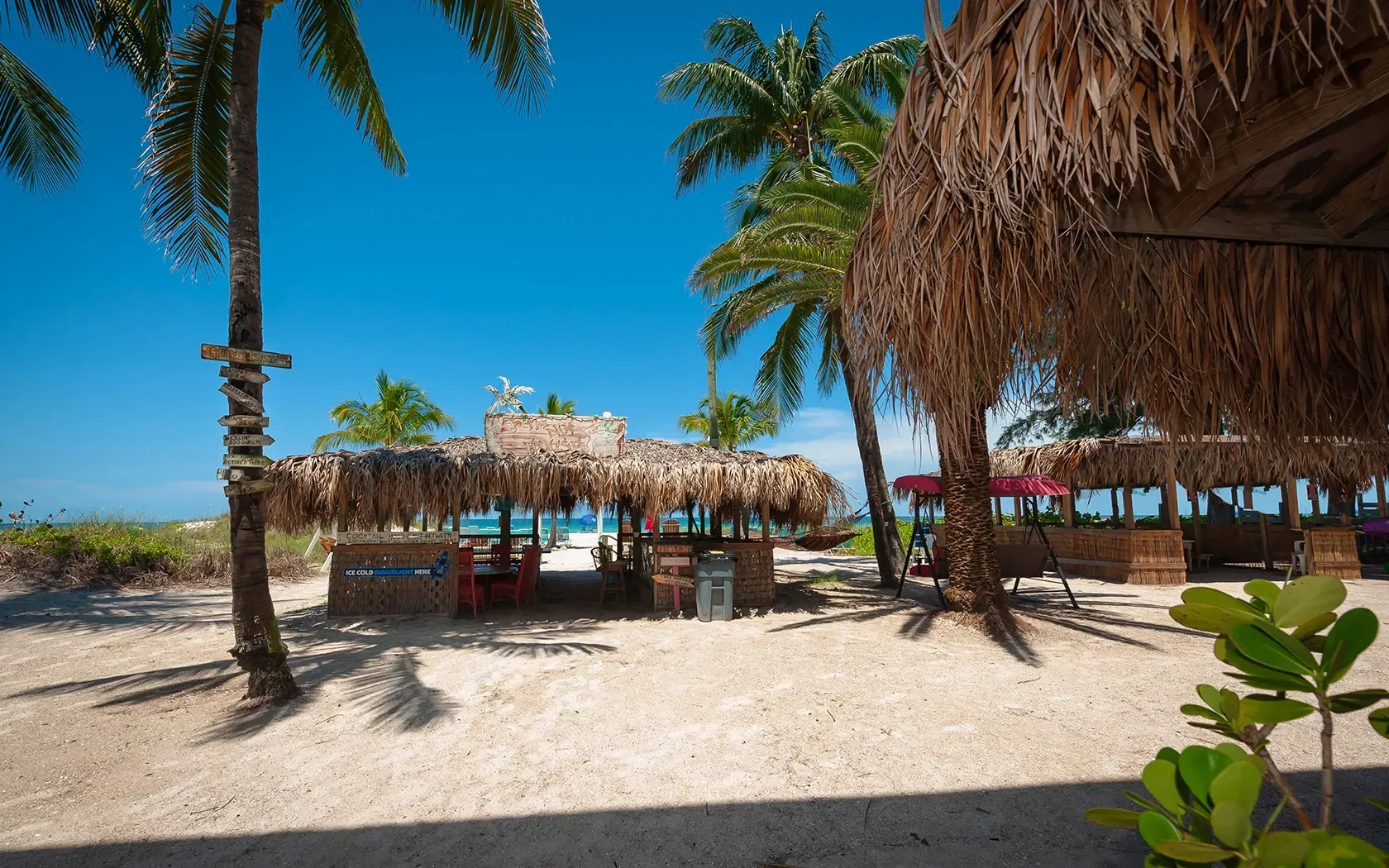 A beach with thatched huts and palm trees on a sunny day