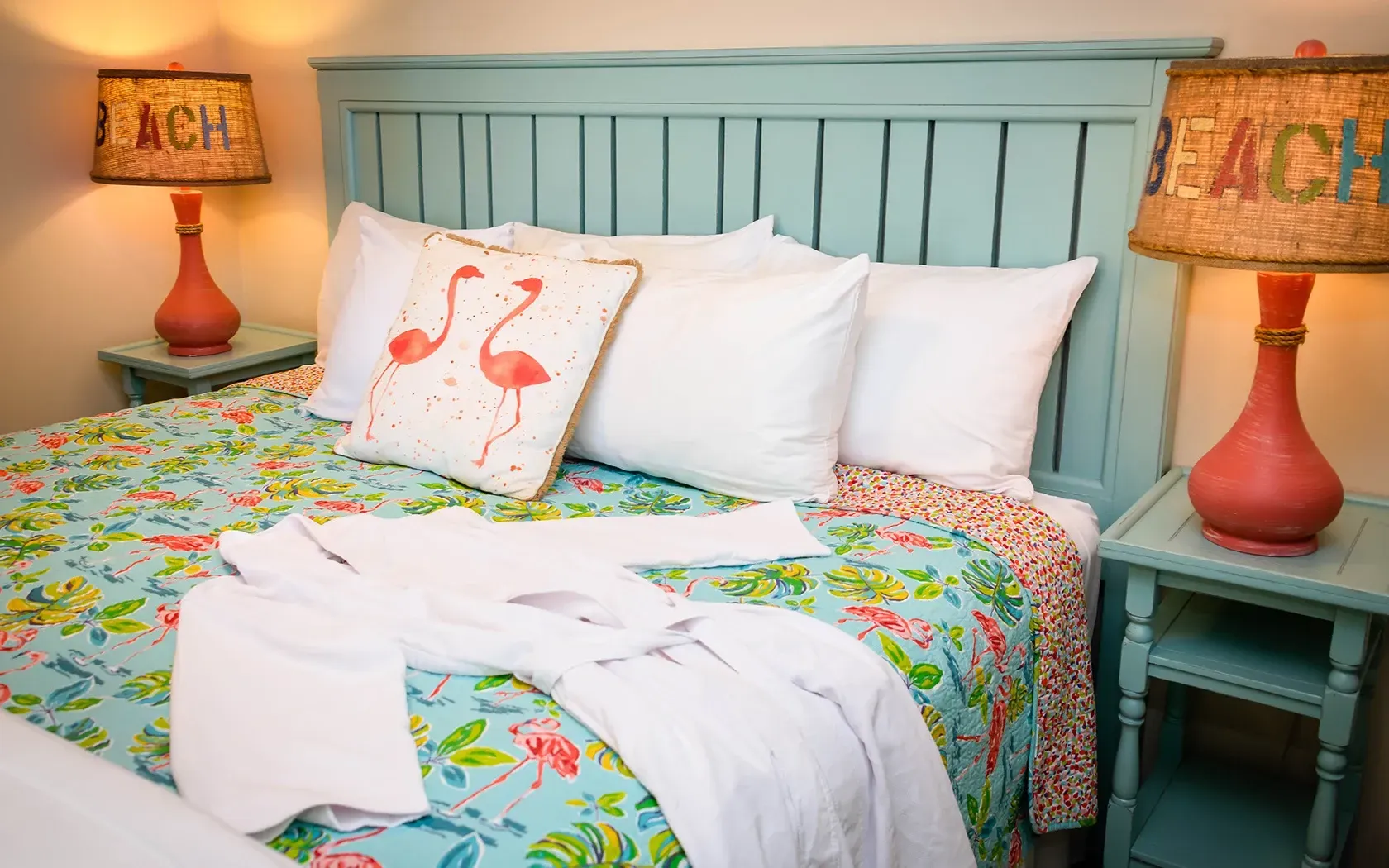 There is a bed with a flamingo pillow on it.