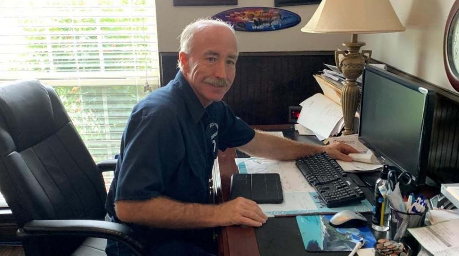 Man seated at desk, typing on keyboard.