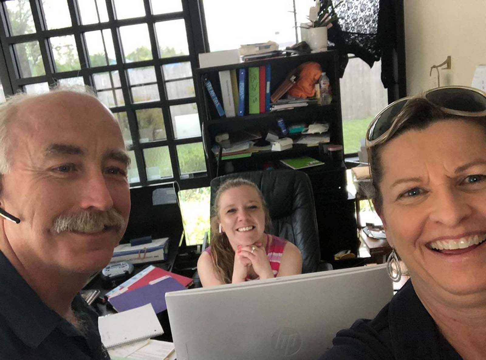 Three people smiling in an office.