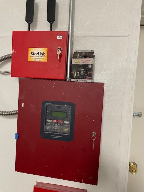 A person in a blue shirt is working on an electrical box on a tiled wall.