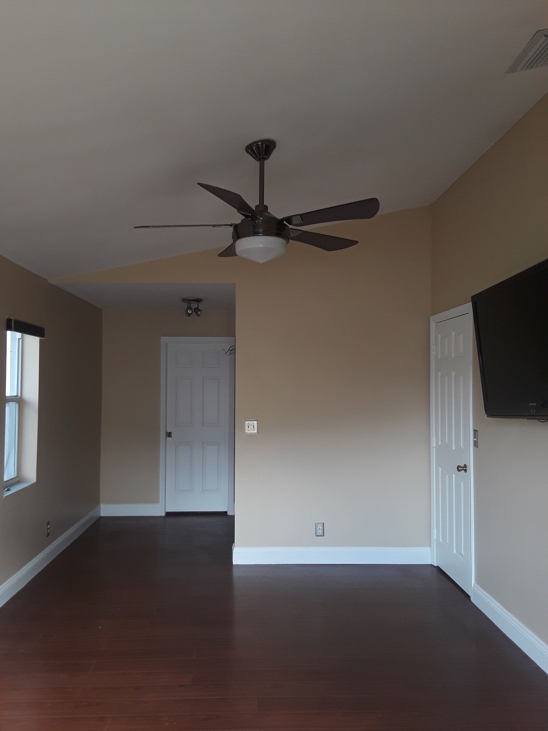 A living room with a ceiling fan and a flat screen tv