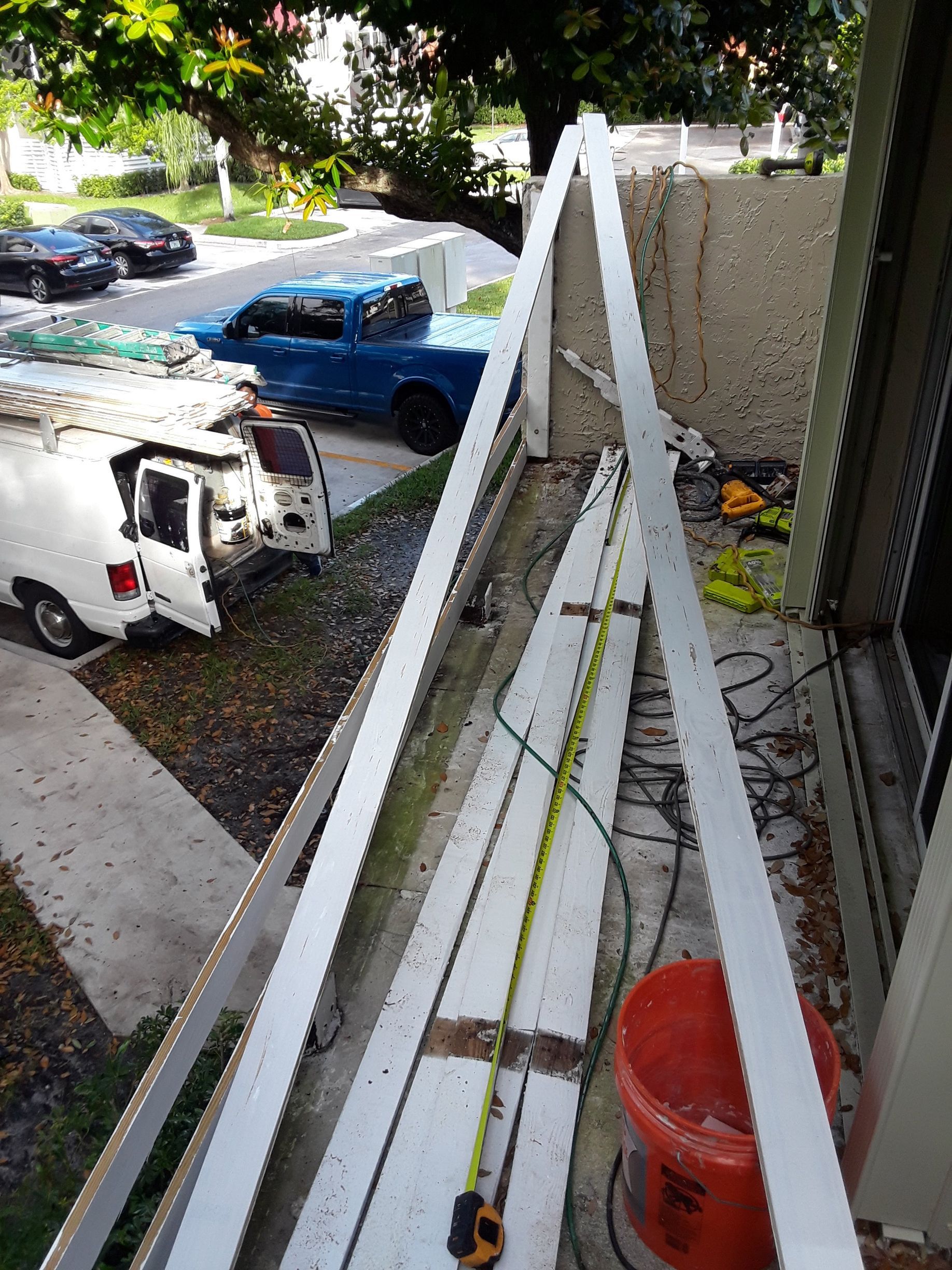 A blue truck is parked on the side of the road next to a white van.