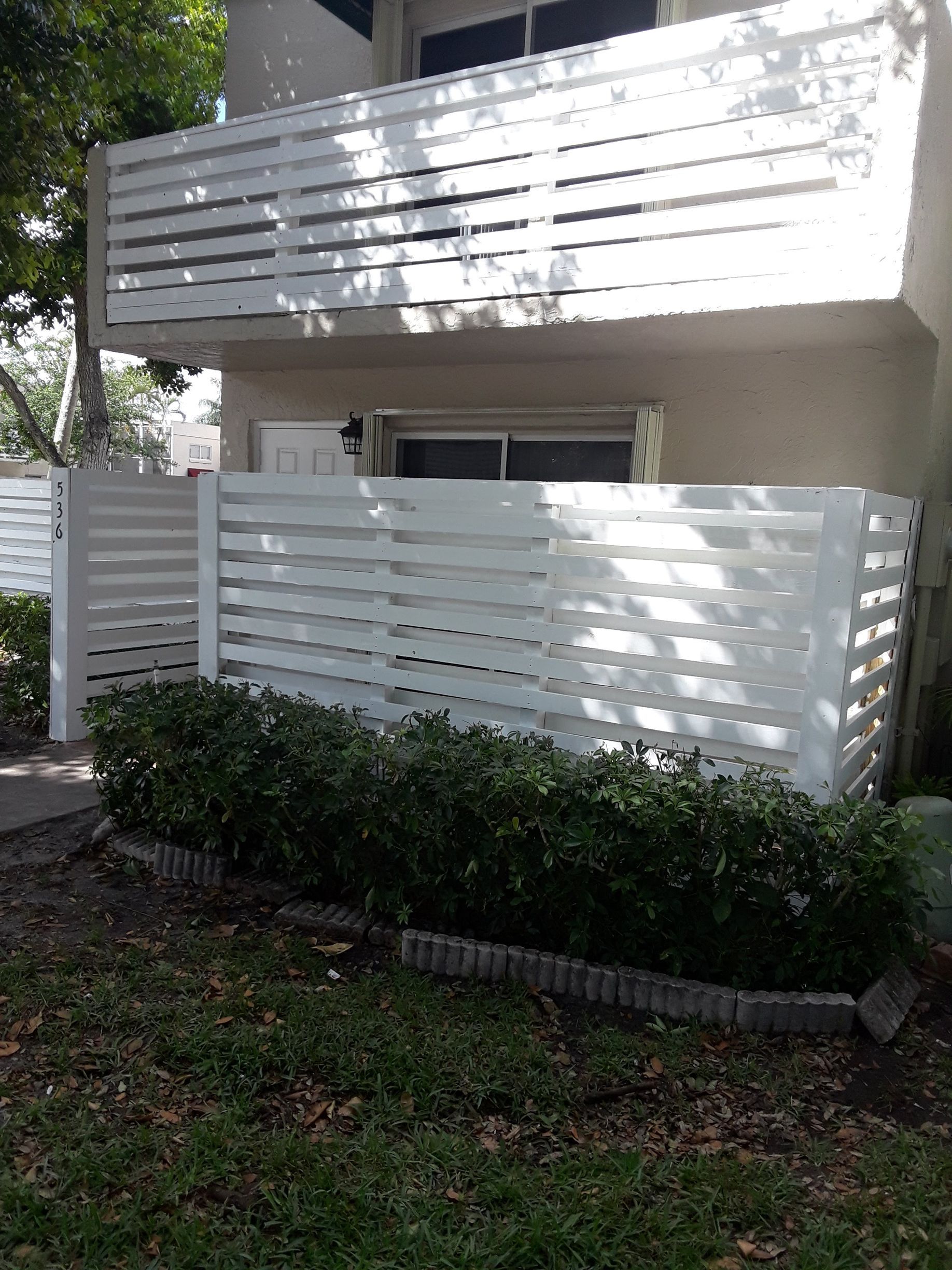 A white fence is in front of a building with a balcony.