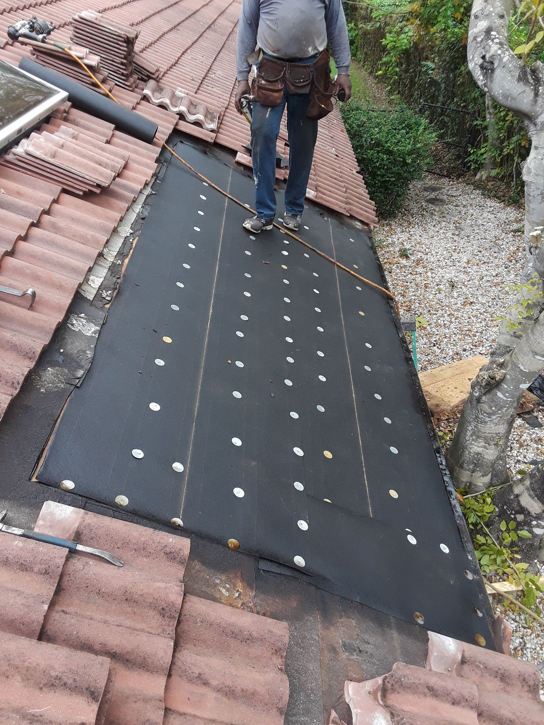 A man is standing on top of a tiled roof.