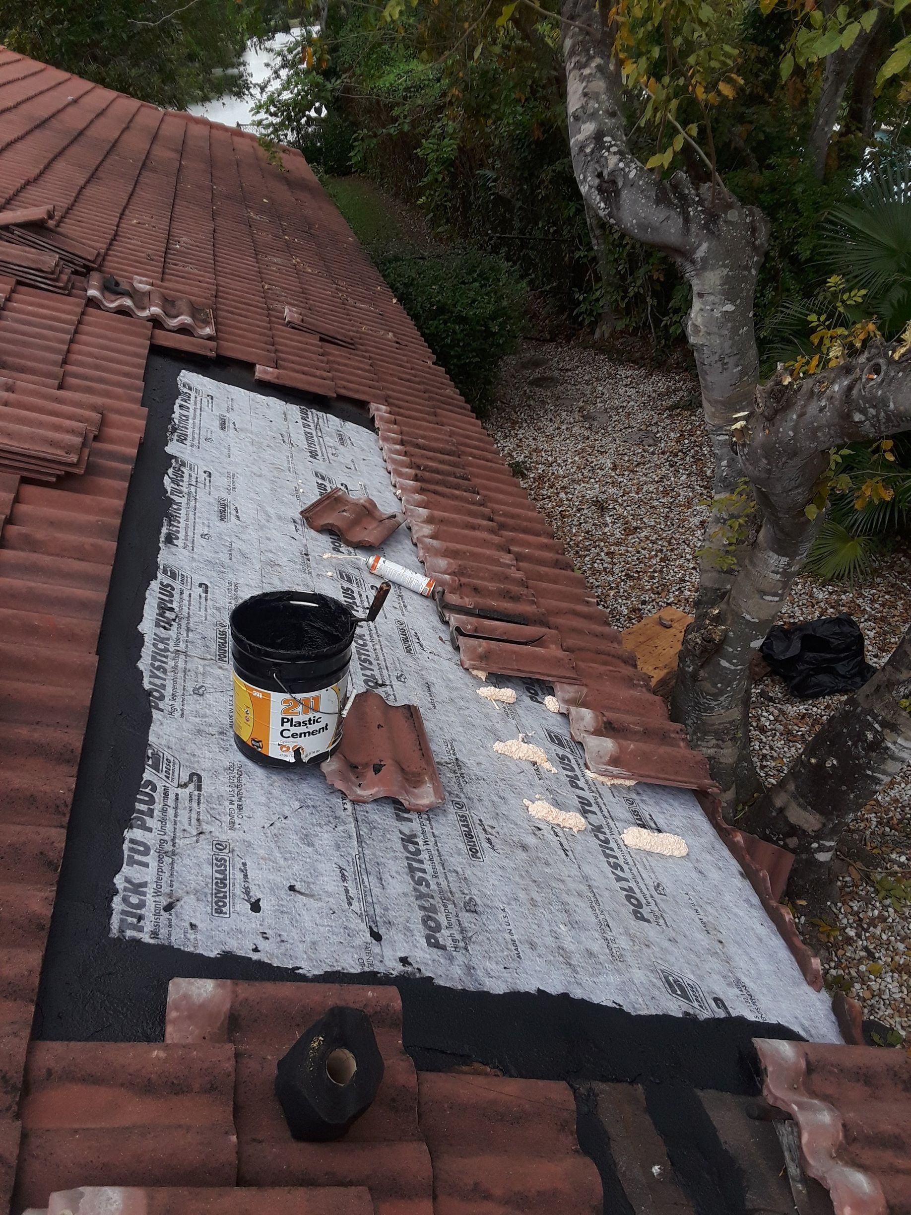 A bucket of paint is sitting on top of a tiled roof.