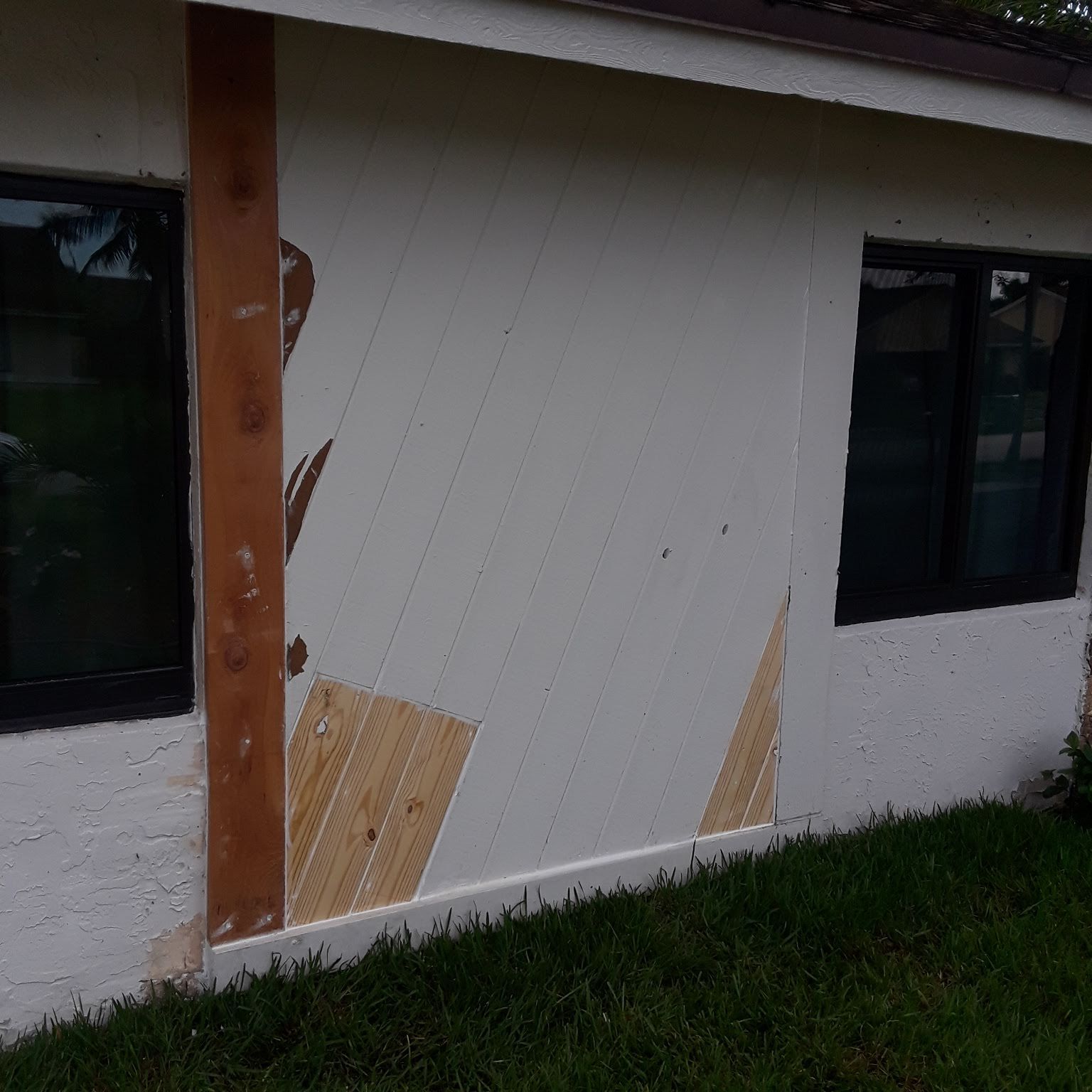 A white house with a wooden post on the side of it.