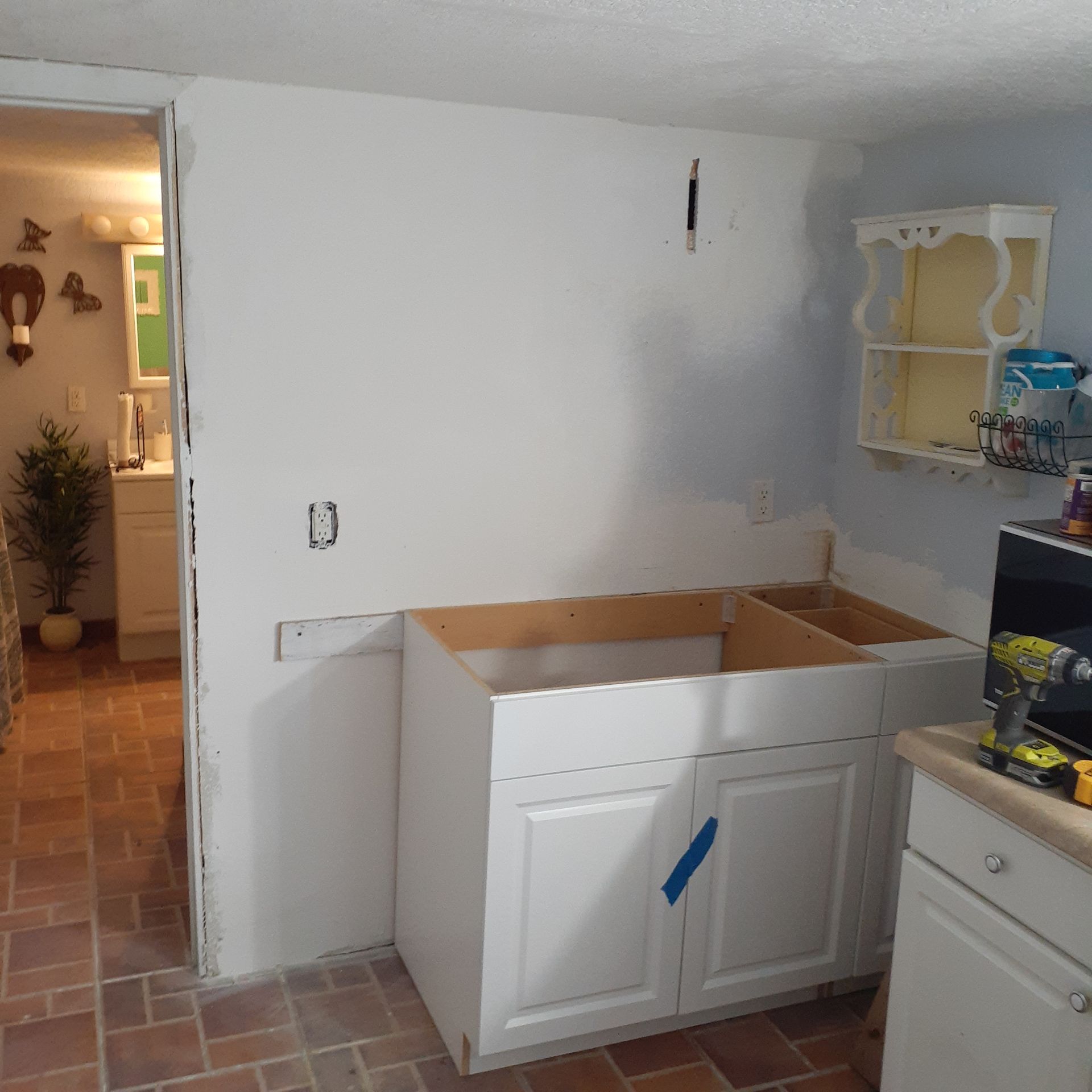 A kitchen with white cabinets and a brick floor