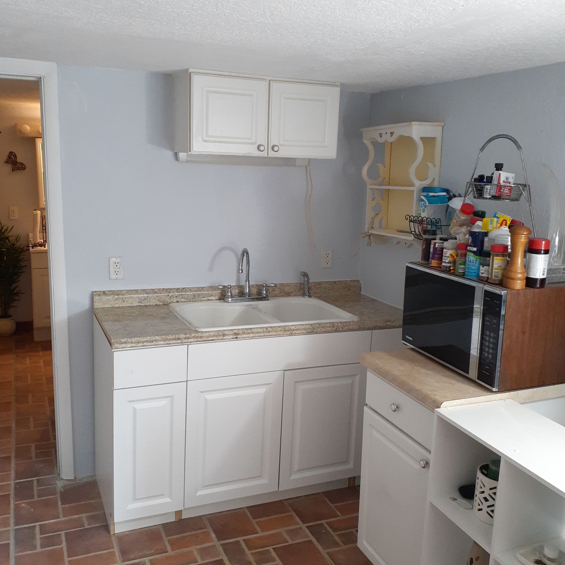 A kitchen with white cabinets a sink and a microwave