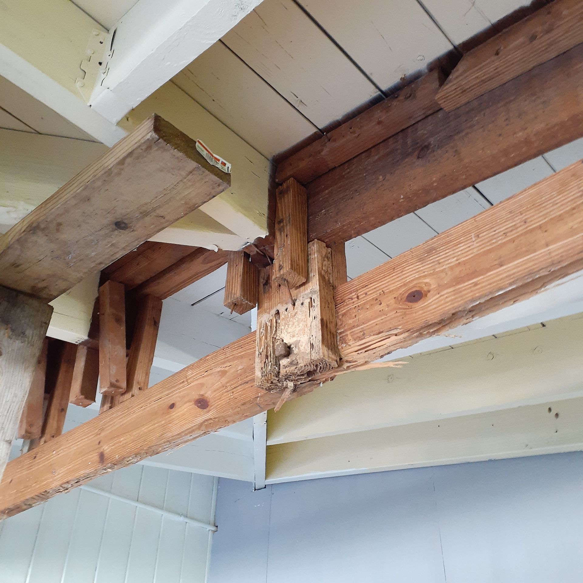 A wooden beam is attached to a white ceiling