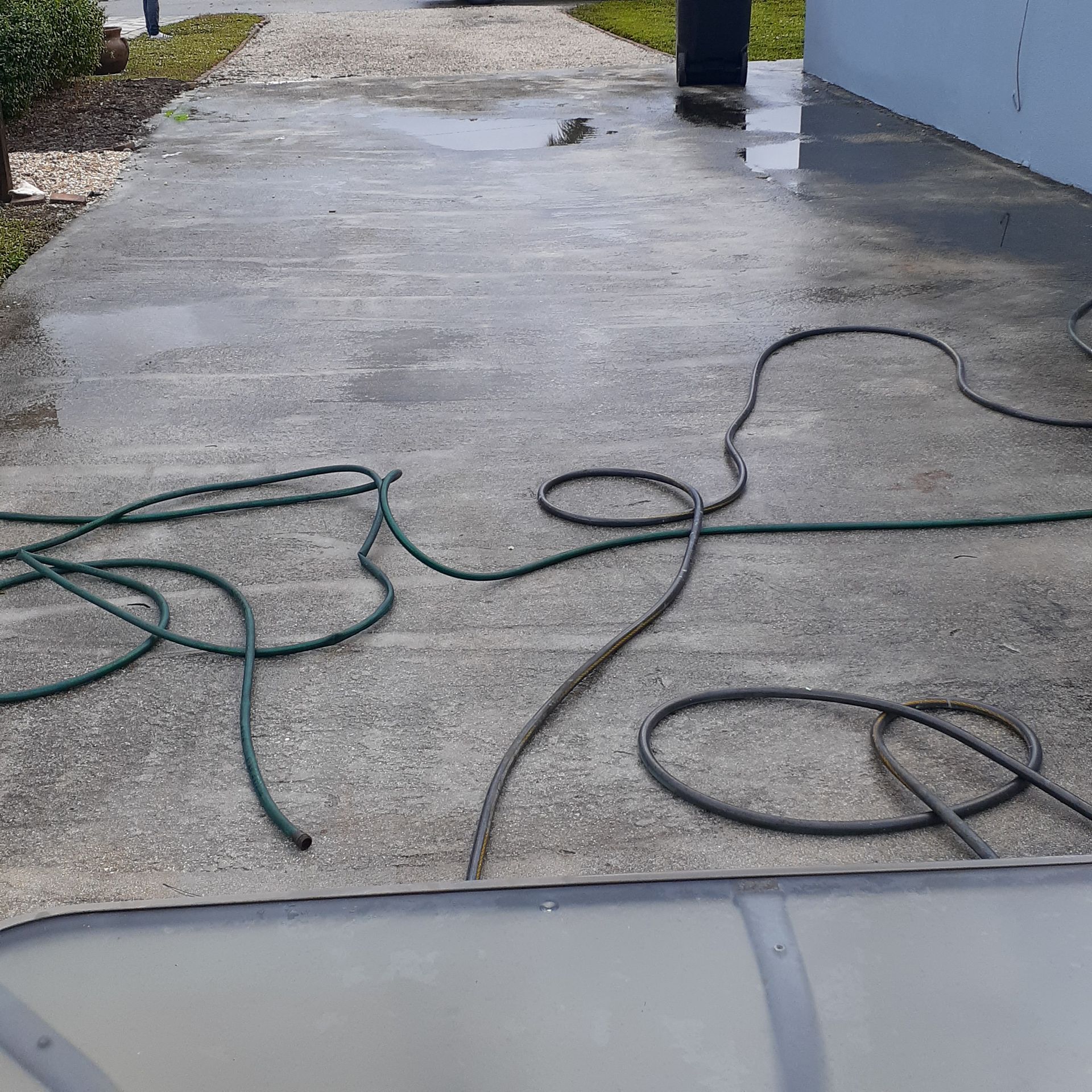 A hose is laying on the ground on a concrete driveway.