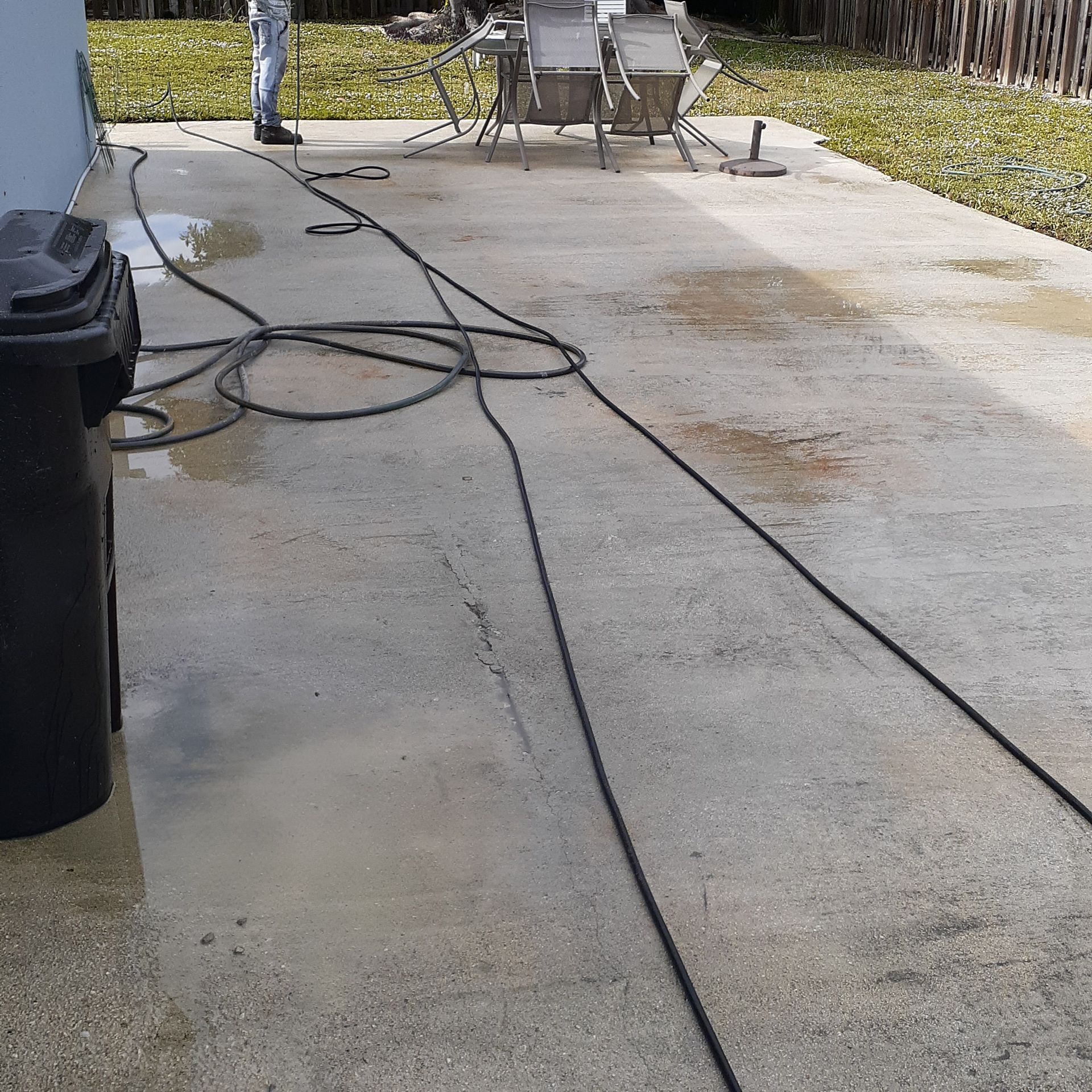A concrete patio with chairs and a trash can