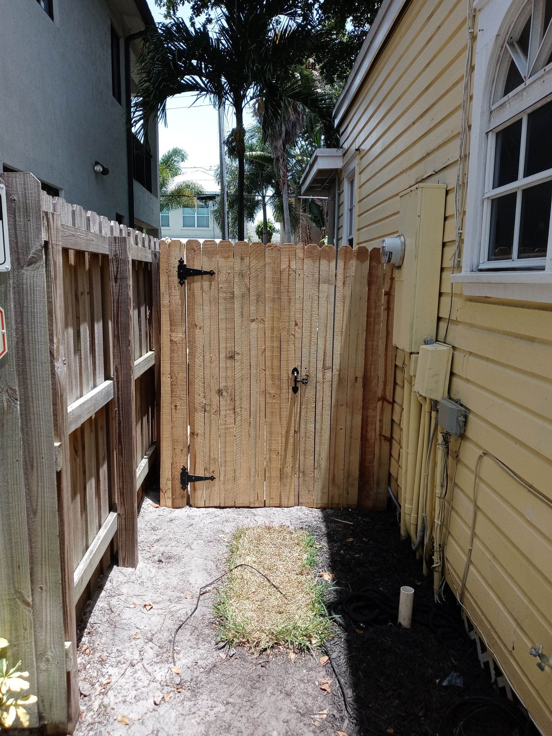 A wooden fence is between two yellow houses