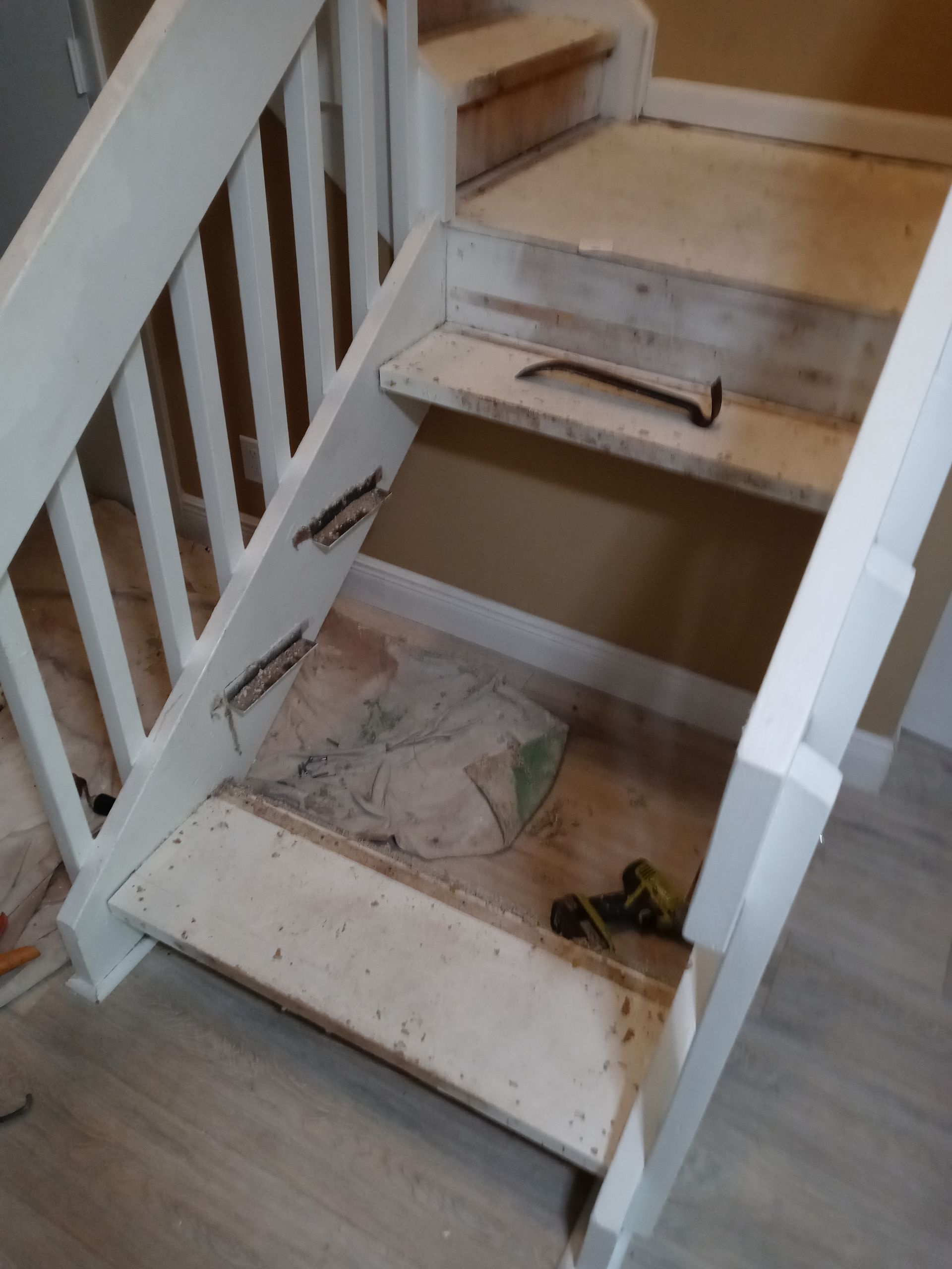 A staircase with a white railing and a hammer on the steps