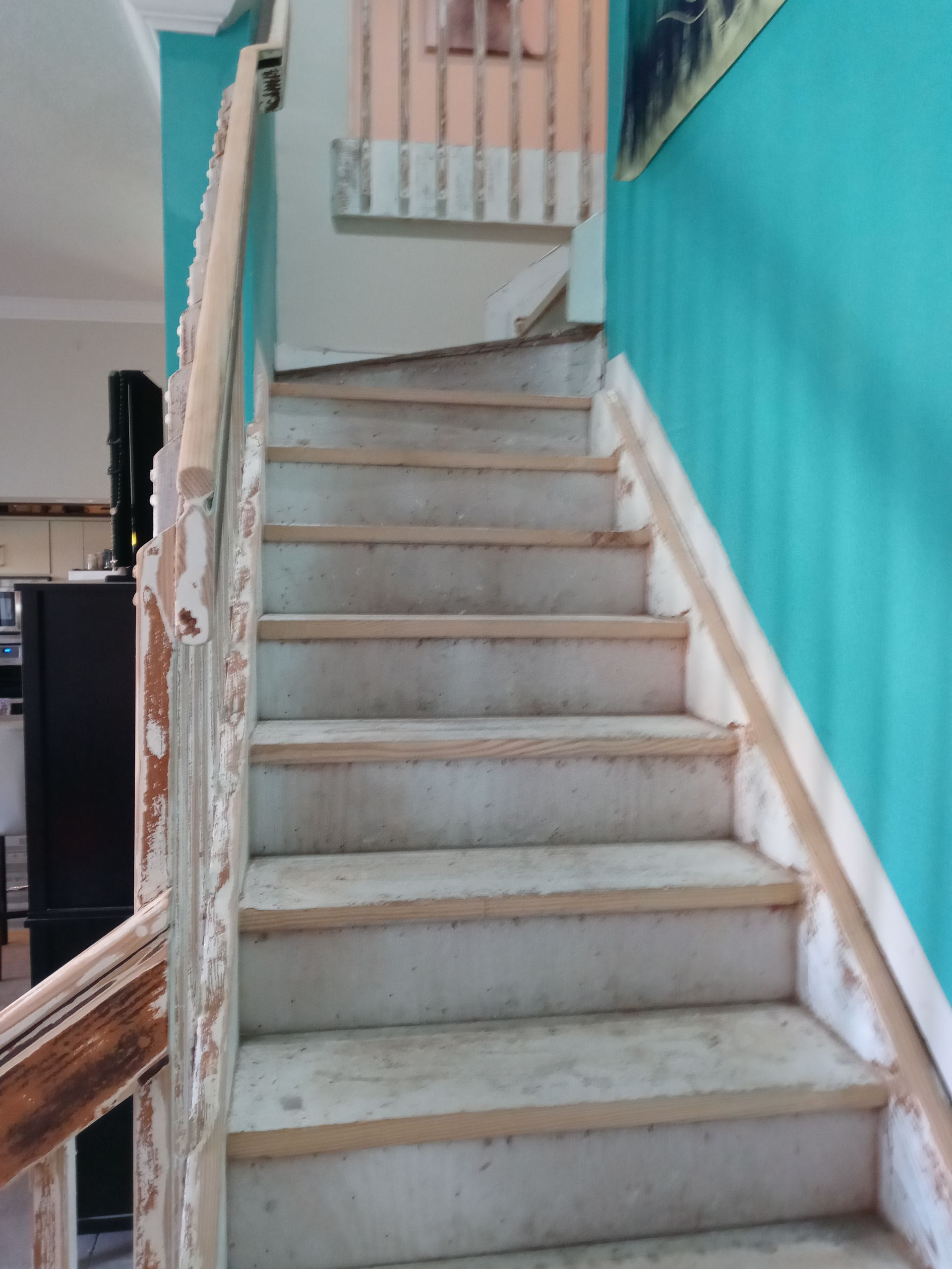 A set of stairs with a wooden railing and a blue wall