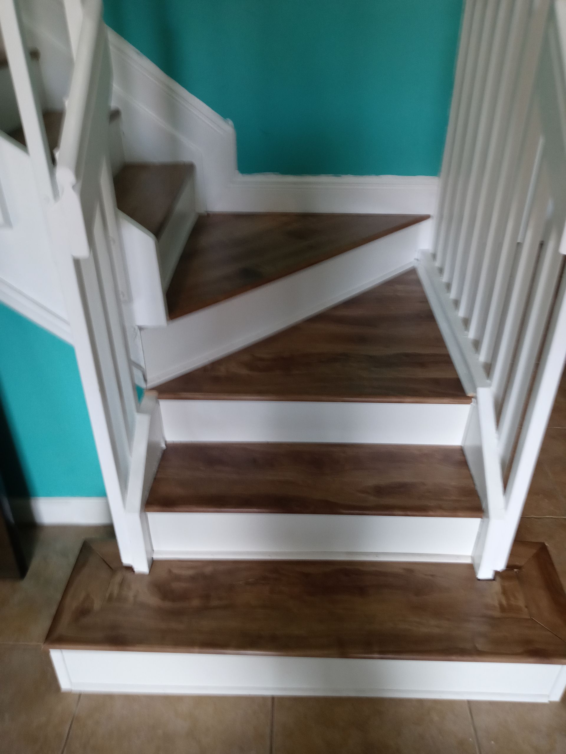 A wooden staircase with a white railing and a blue wall