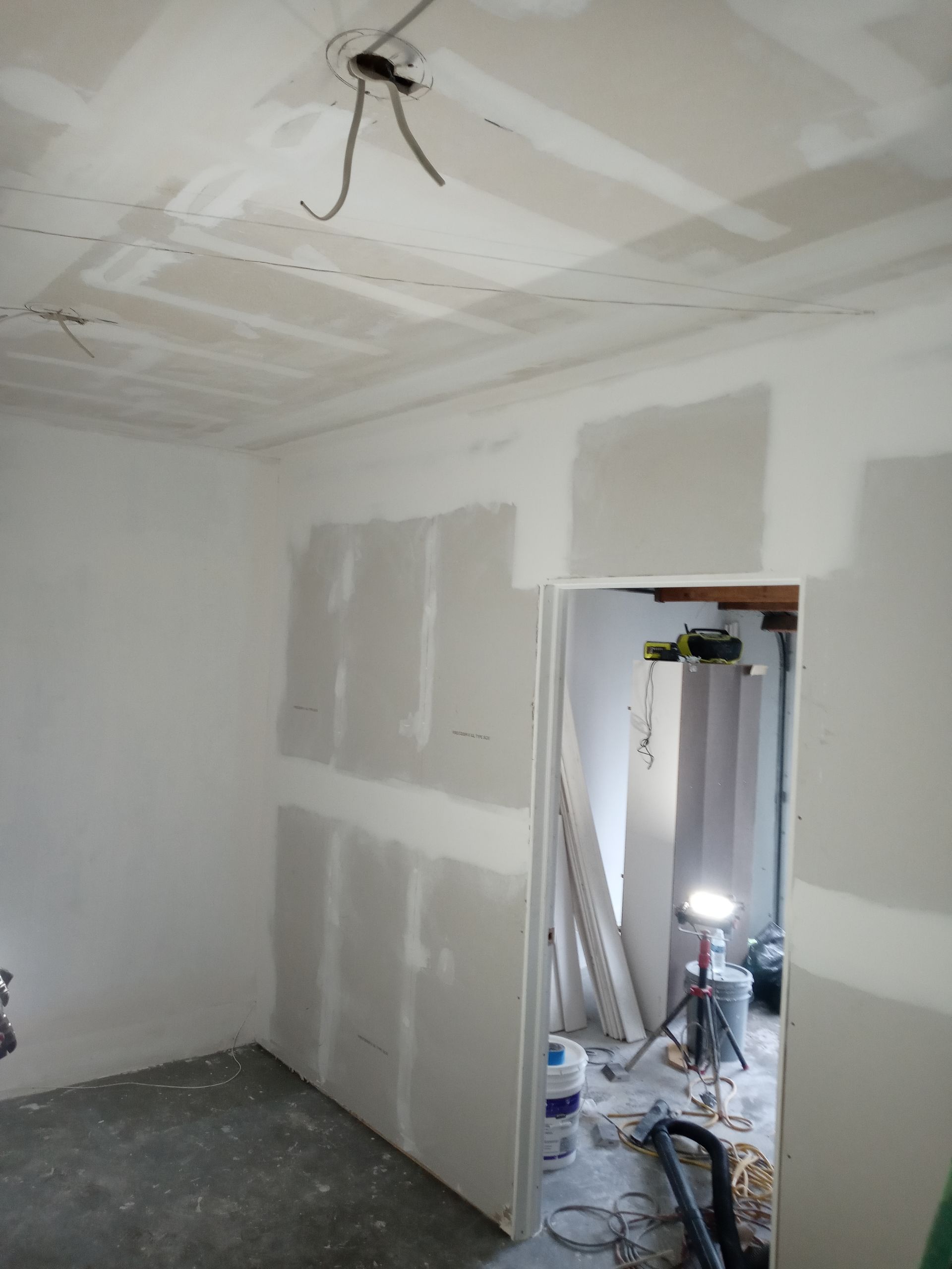 A room with white walls and a door that is being remodeled.