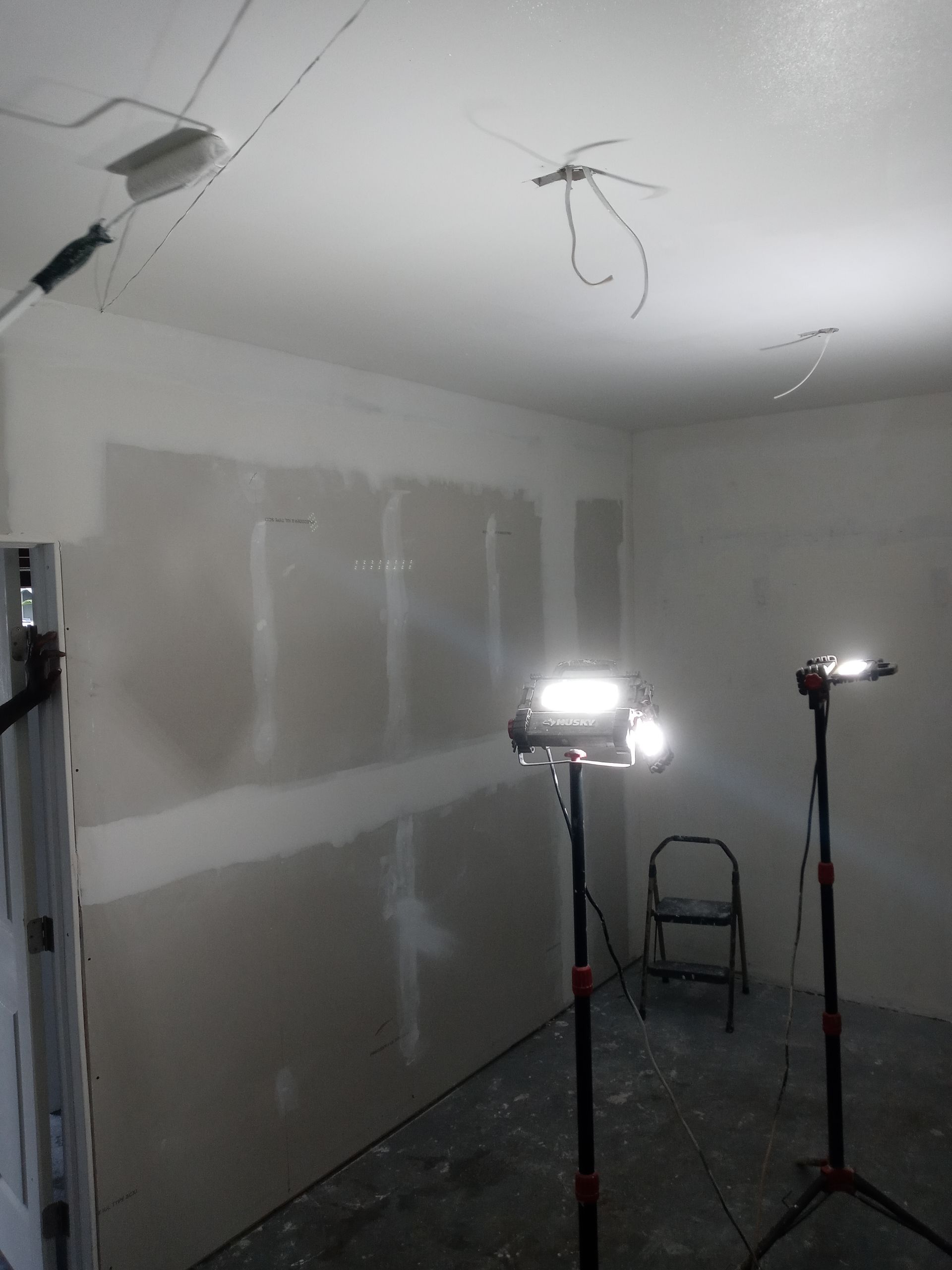 A room with a ladder and two lights in it
