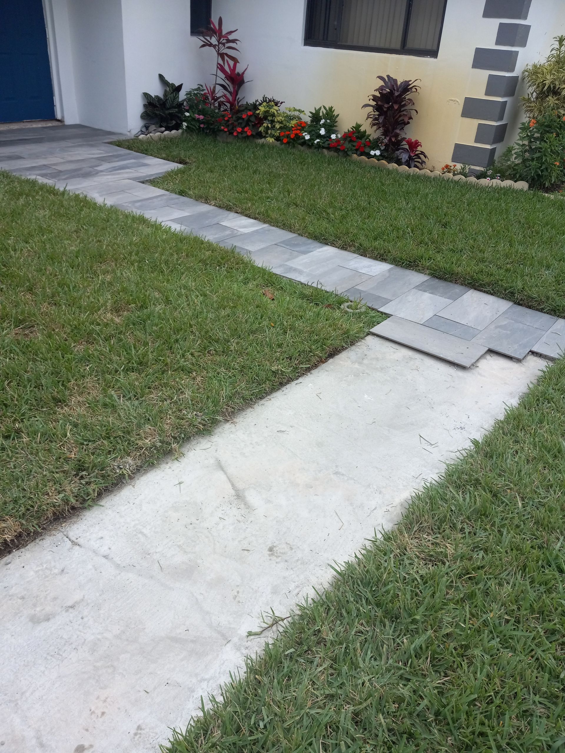 A sidewalk leading to a house with a blue door