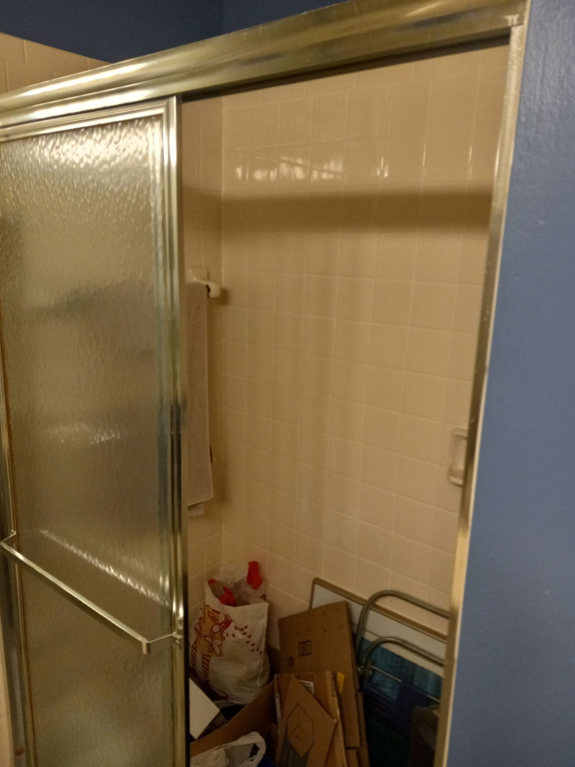 A bathroom with a sliding glass shower door and a towel rack.