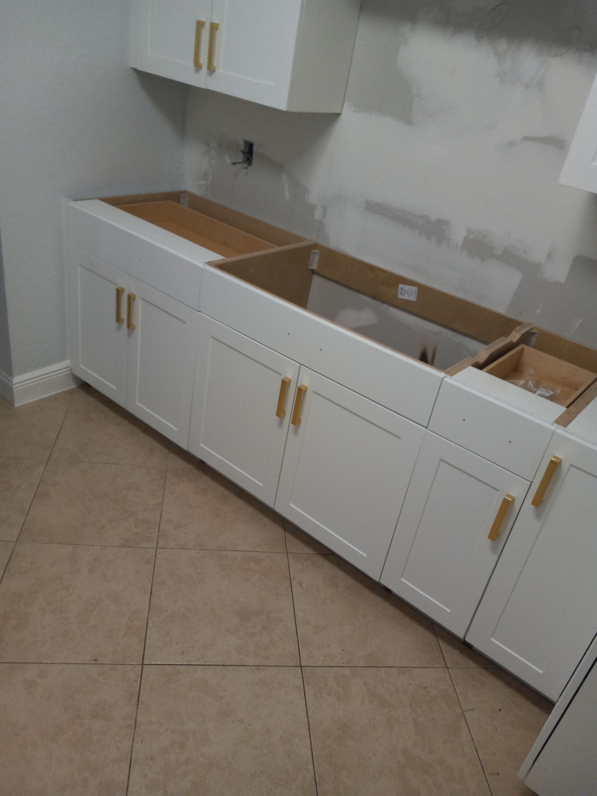 A kitchen under construction with white cabinets and a sink