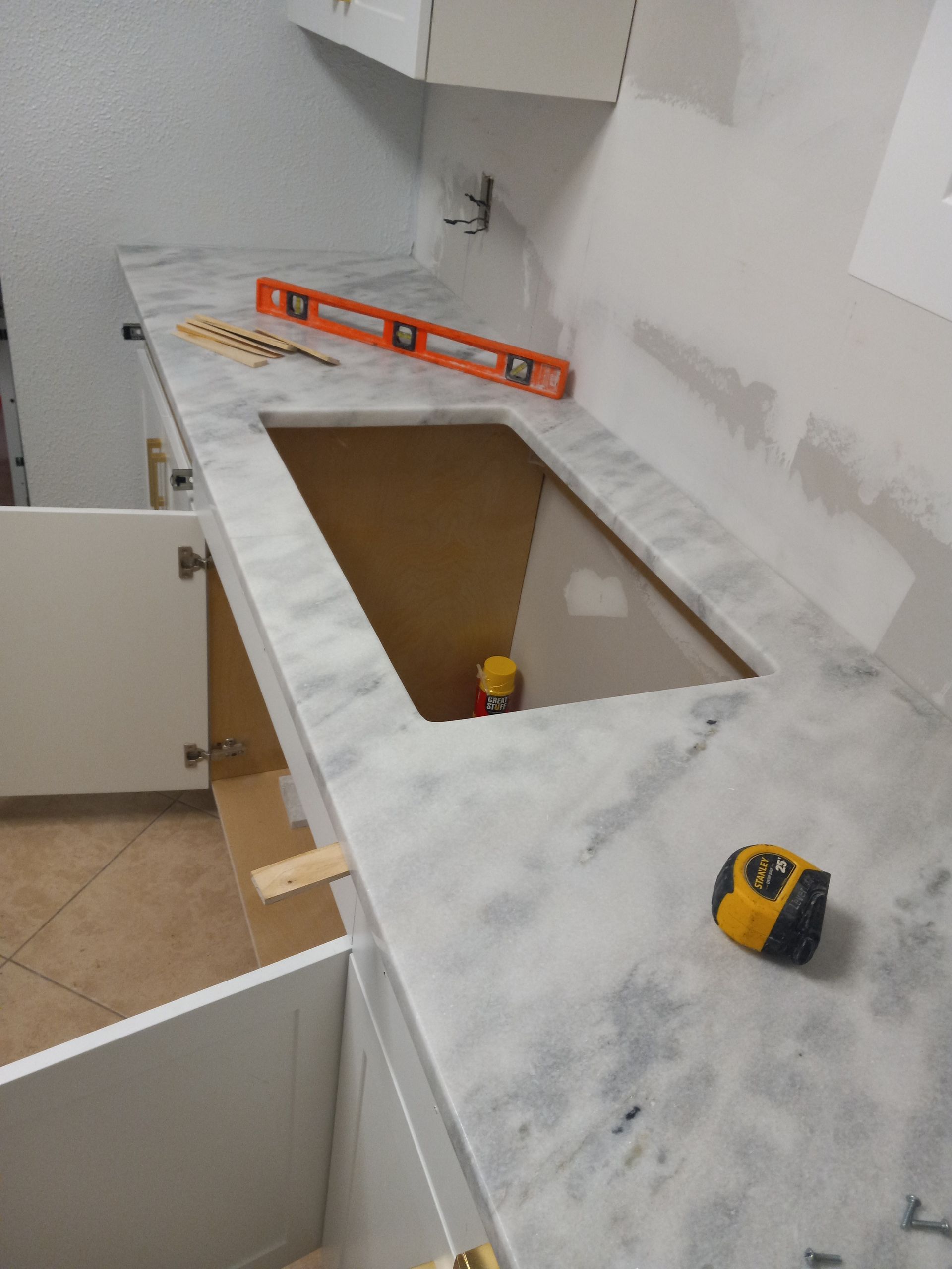 A measuring tape sits on a counter next to a level