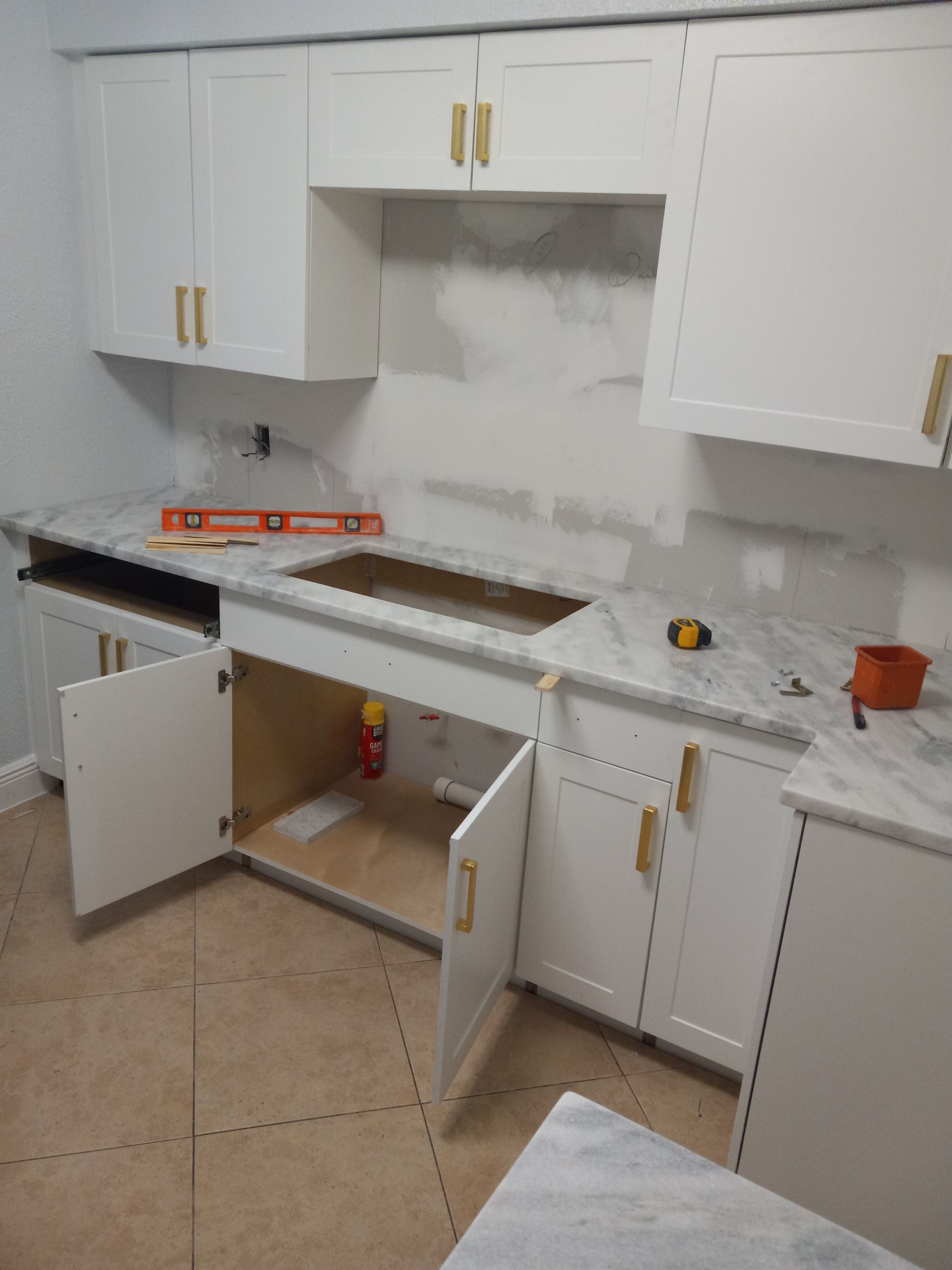 A kitchen with white cabinets and marble counter tops