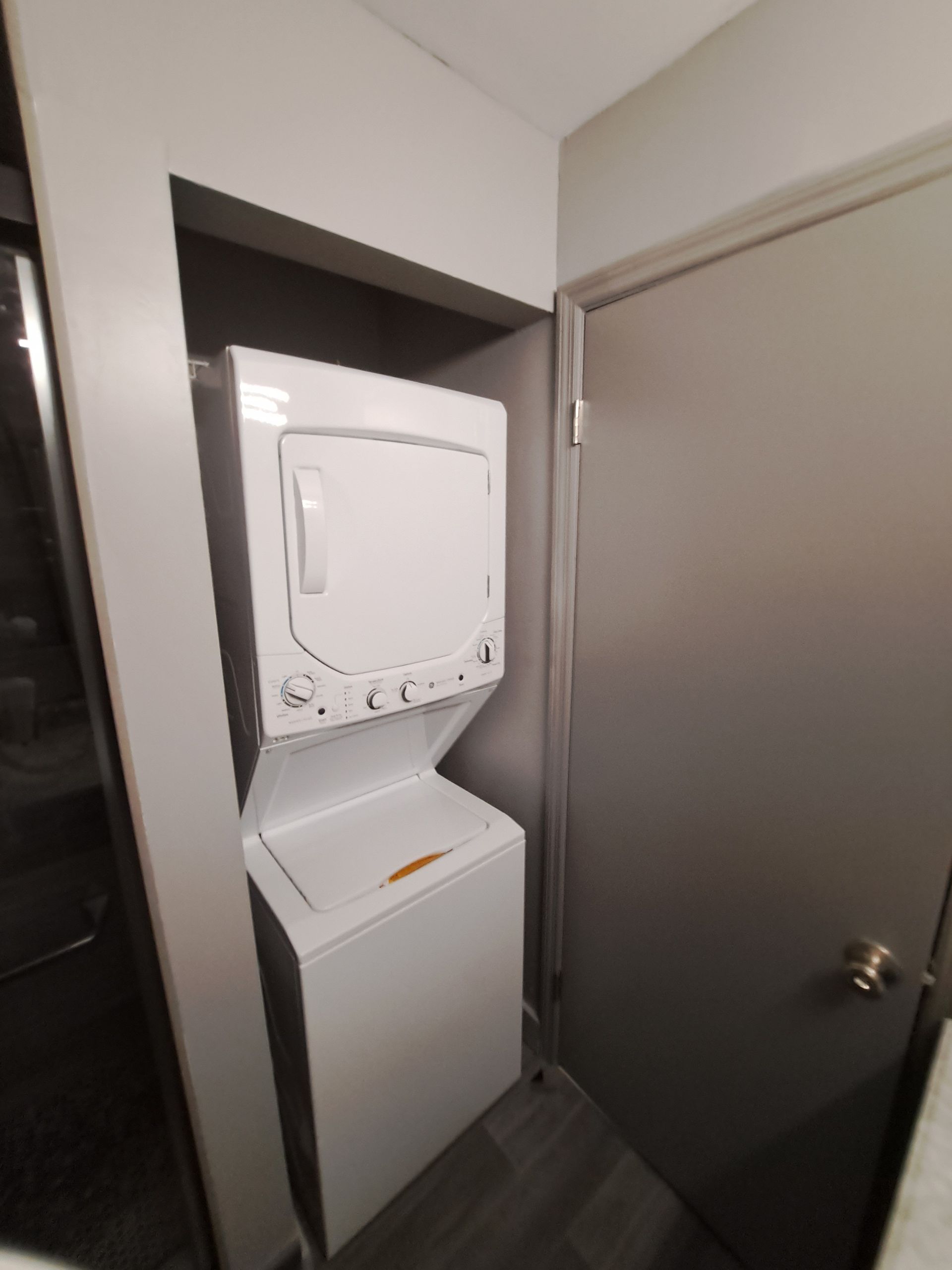 A washer and dryer are stacked on top of each other in a closet.