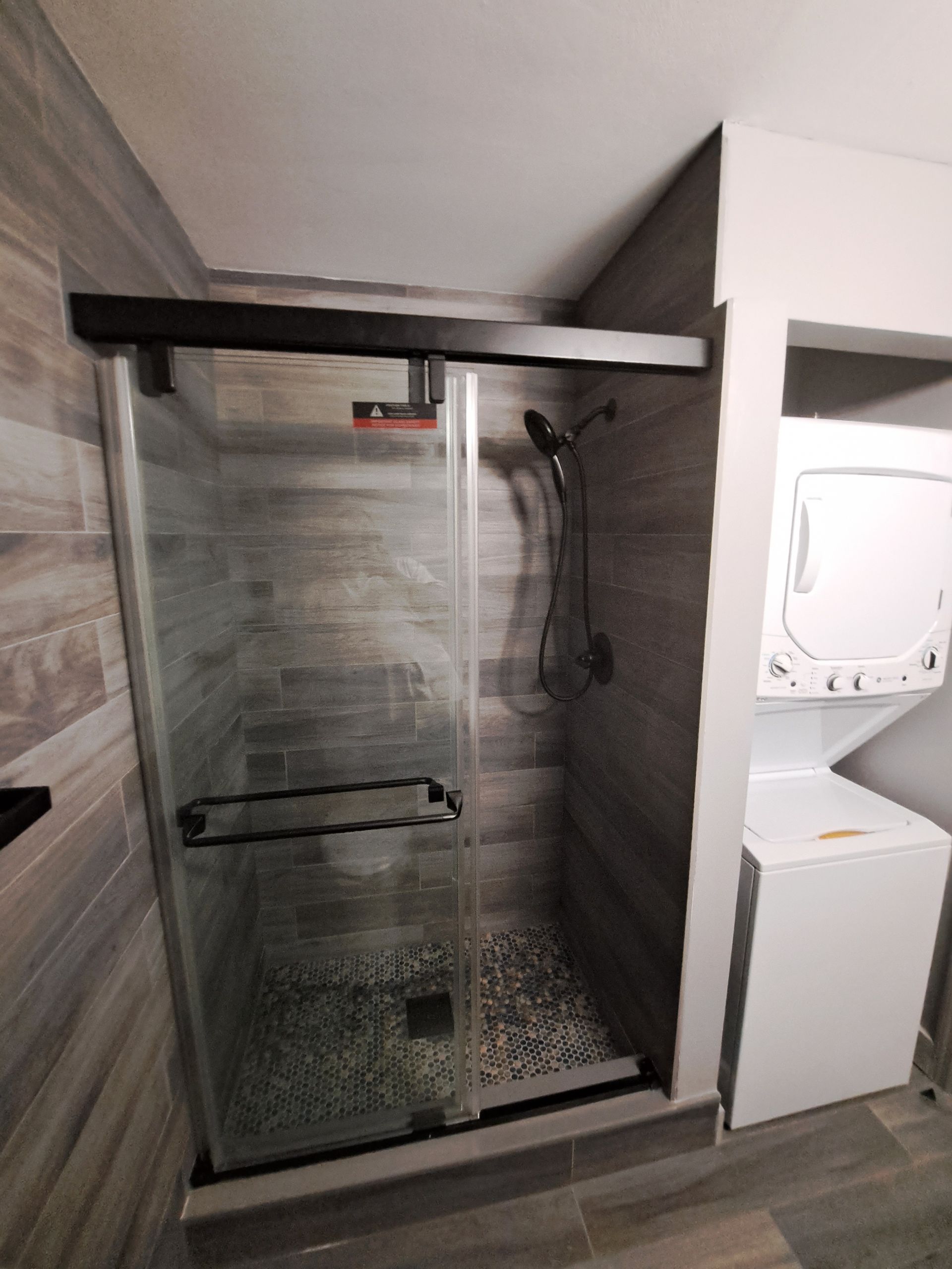 A bathroom with a shower and a washer and dryer.