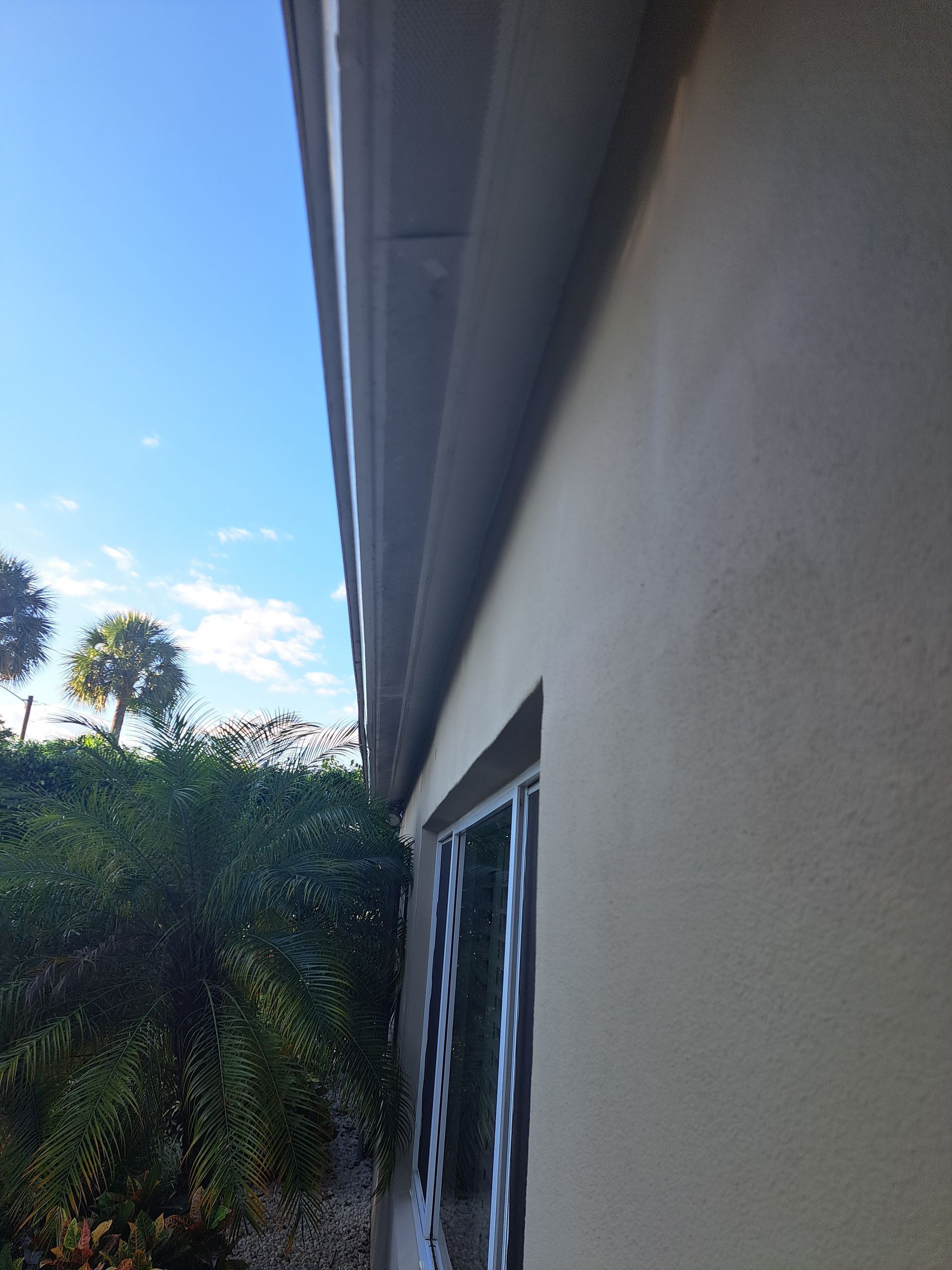 The side of a building with a window and a blue sky in the background.