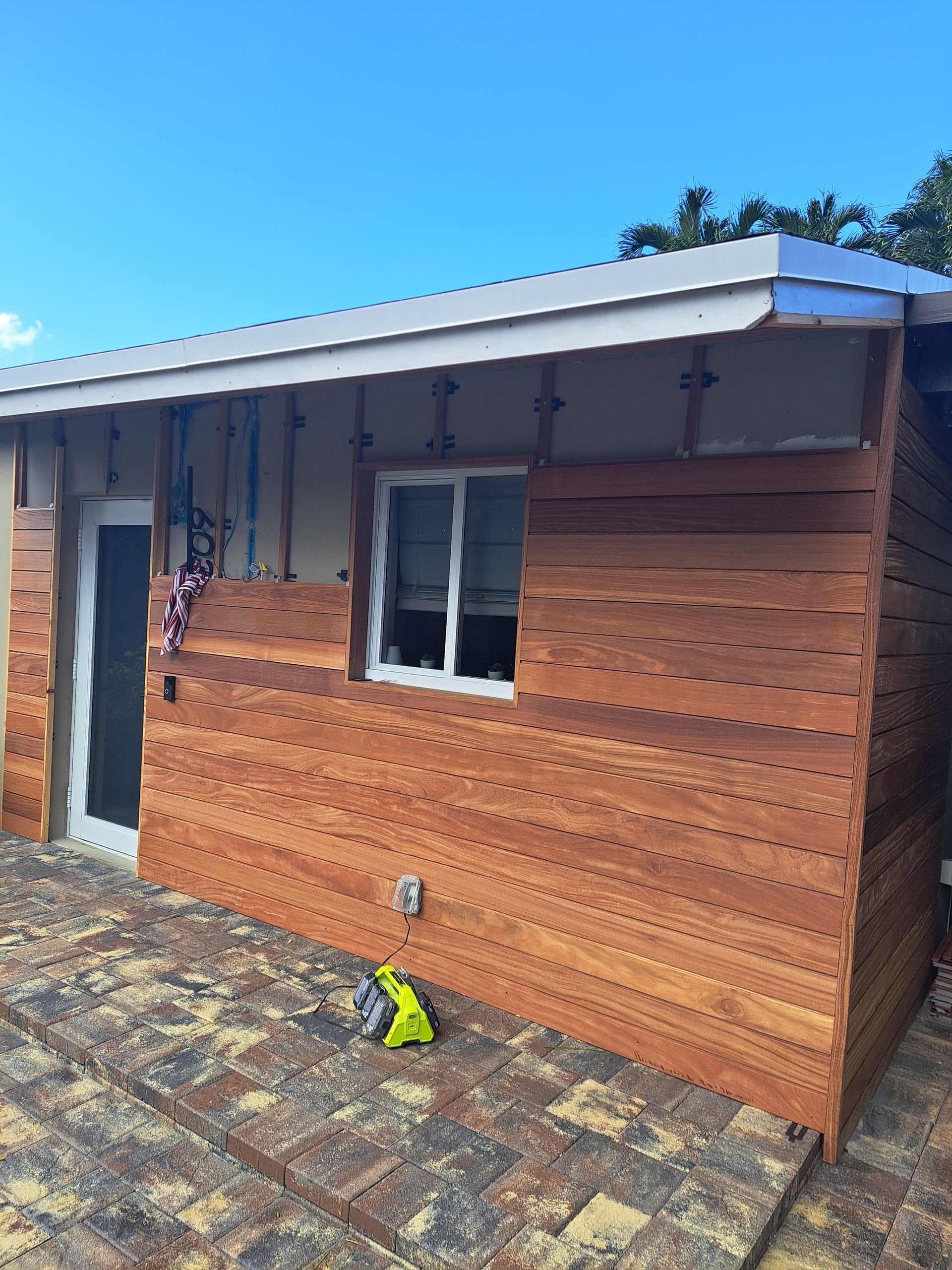 A small wooden house with a window and a door is being built.