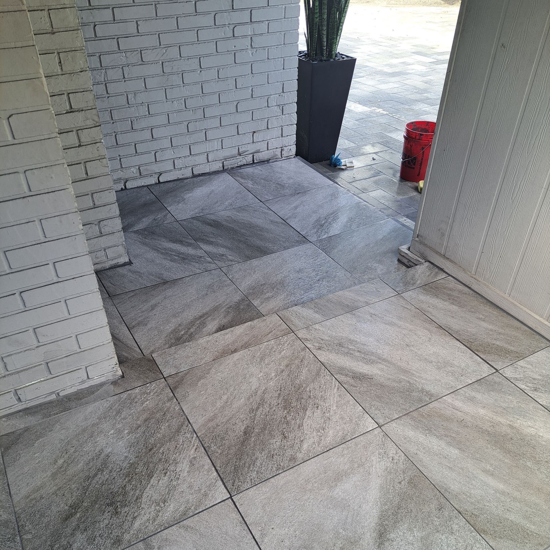 A tiled floor with a white brick wall in the background.