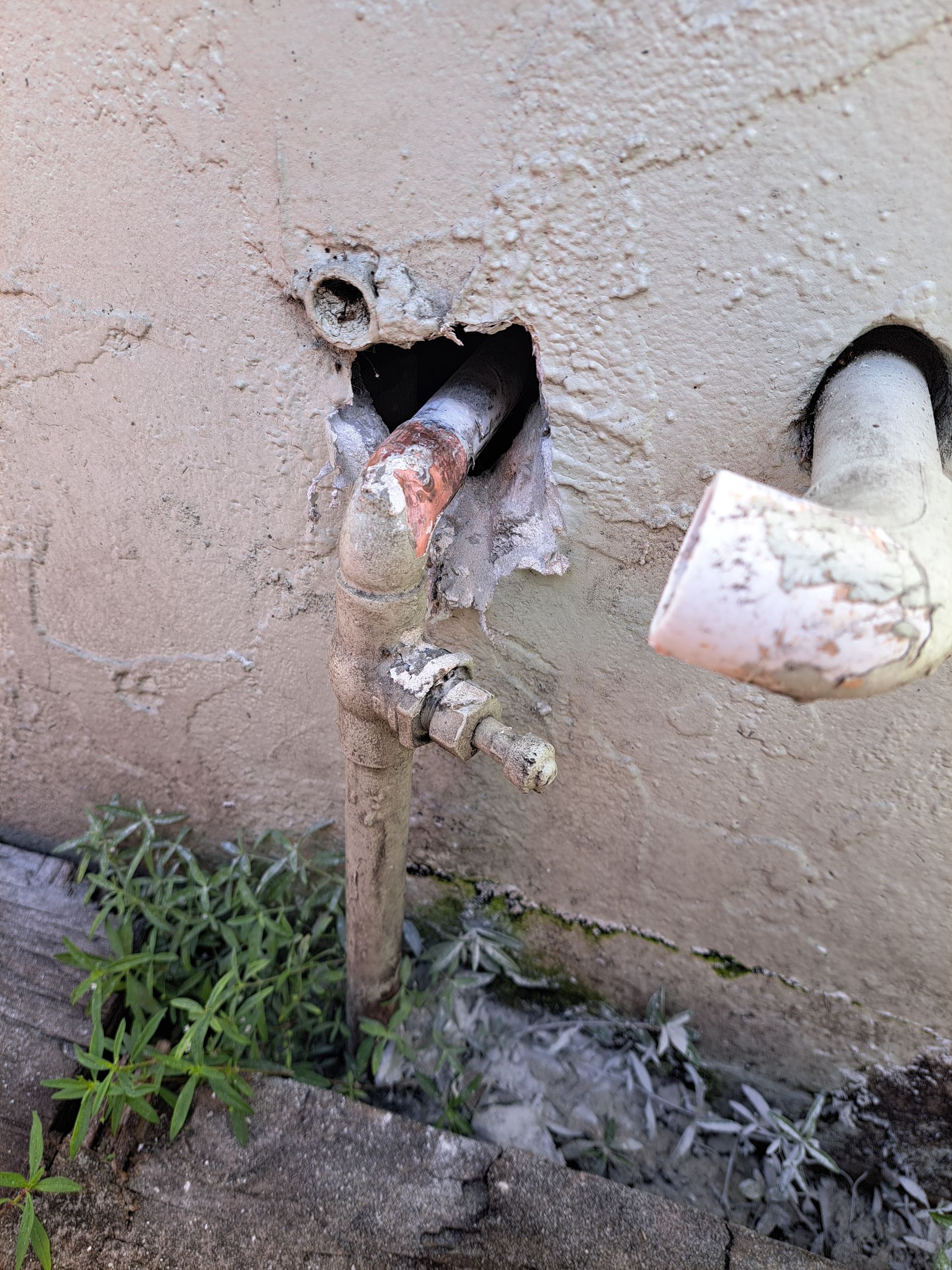 A pipe is coming out of a hole in a wall.
