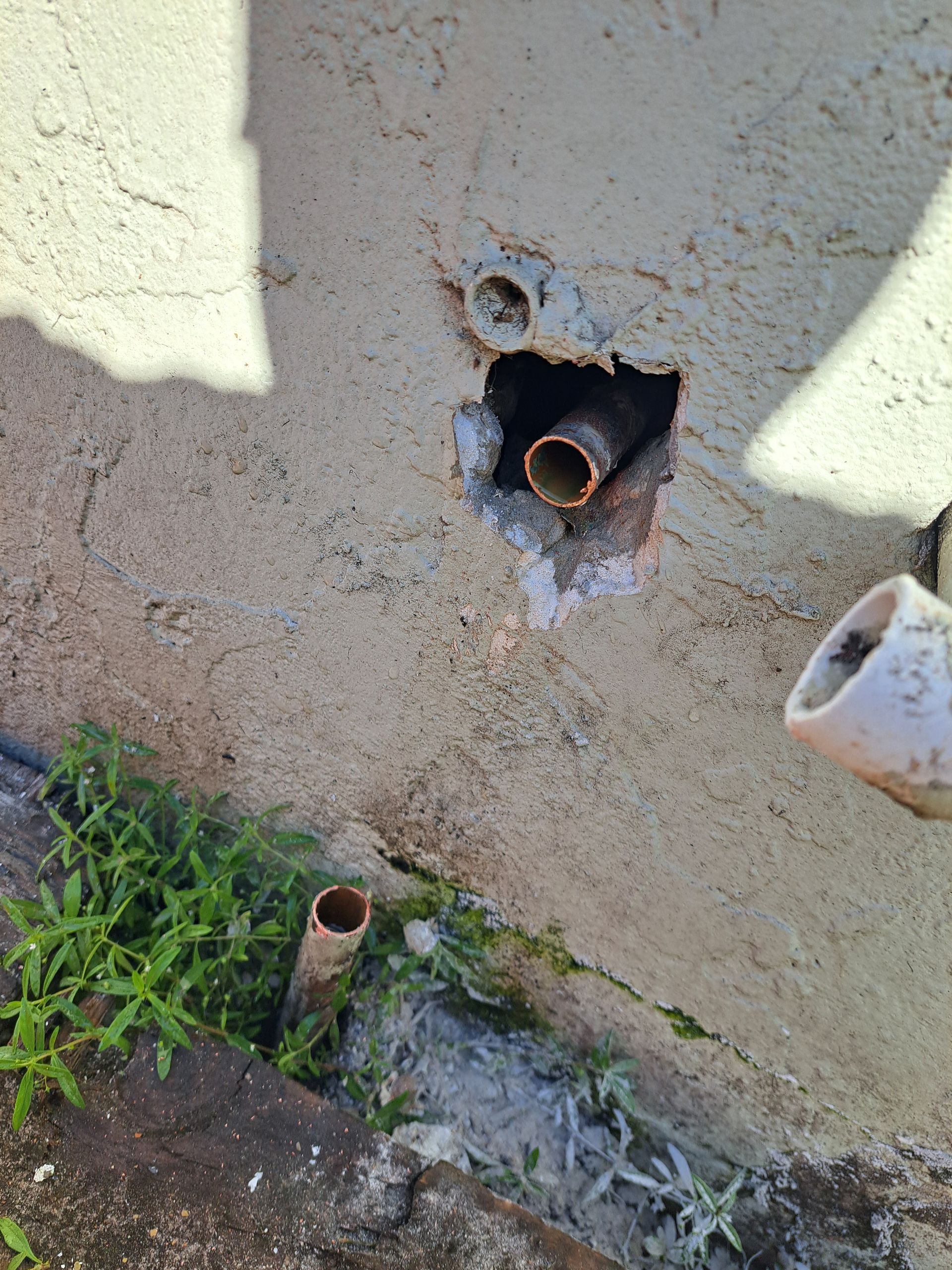 A hole in a wall with a pipe coming out of it.