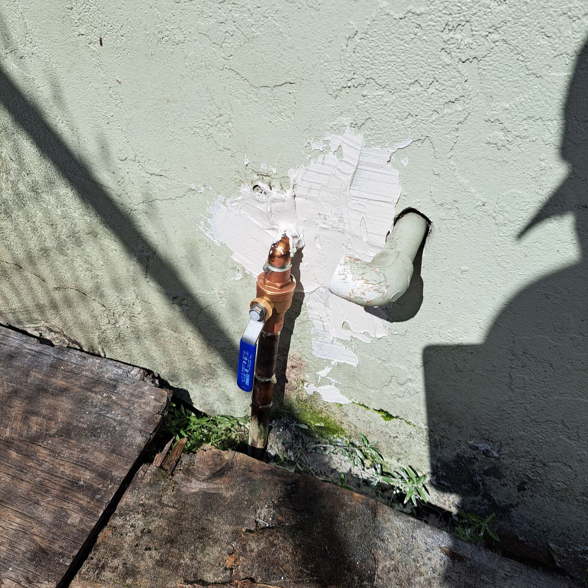 A shadow of a person is cast on a wall next to a faucet.