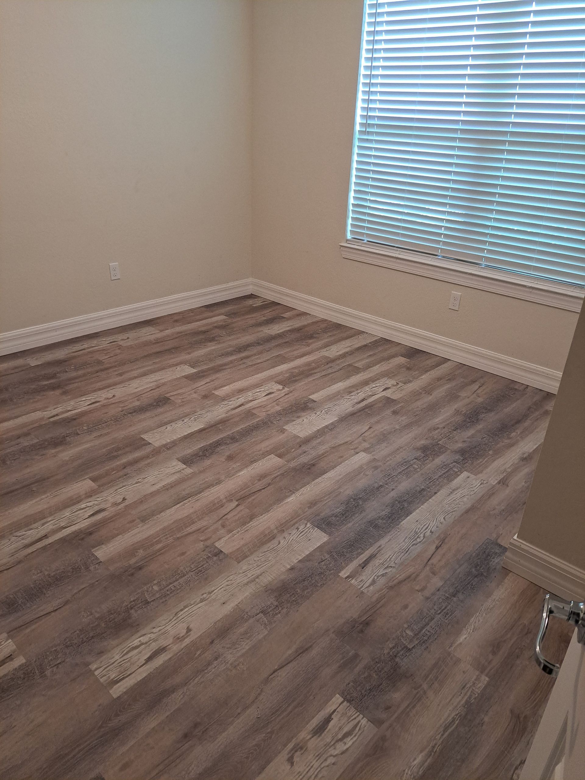 A bedroom with hardwood floors and a window.