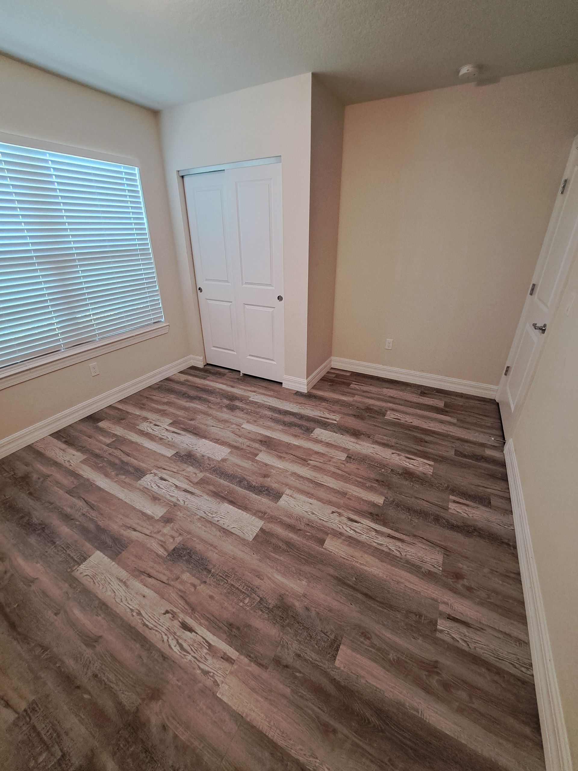 A bedroom with hardwood floors and a window.