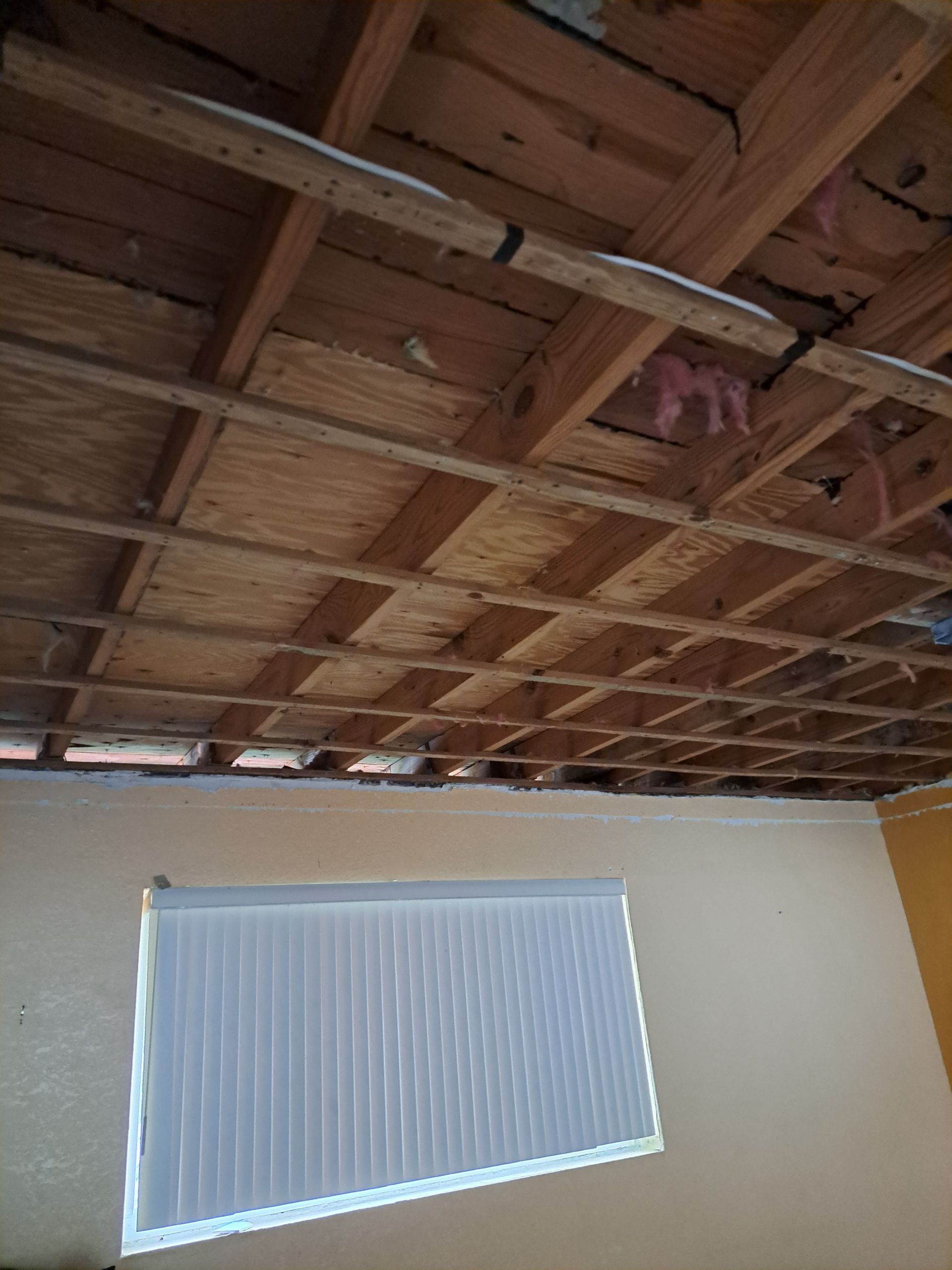 A room with a window and a wooden ceiling.