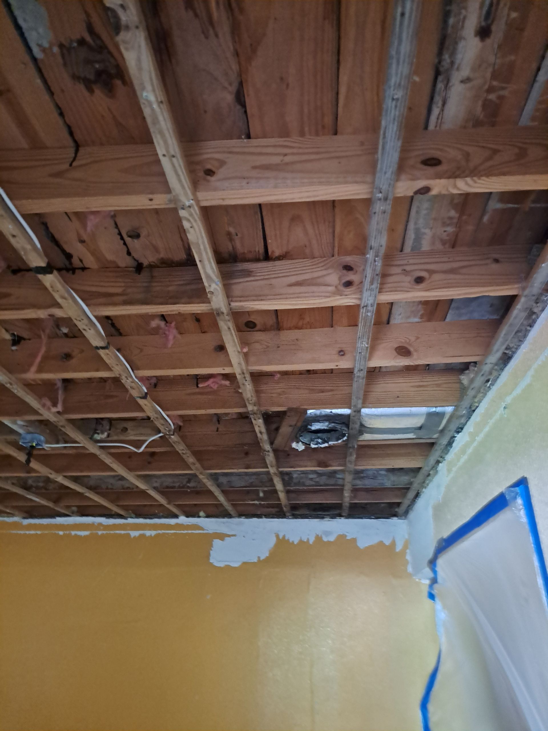 A room with a wooden ceiling and a yellow wall.