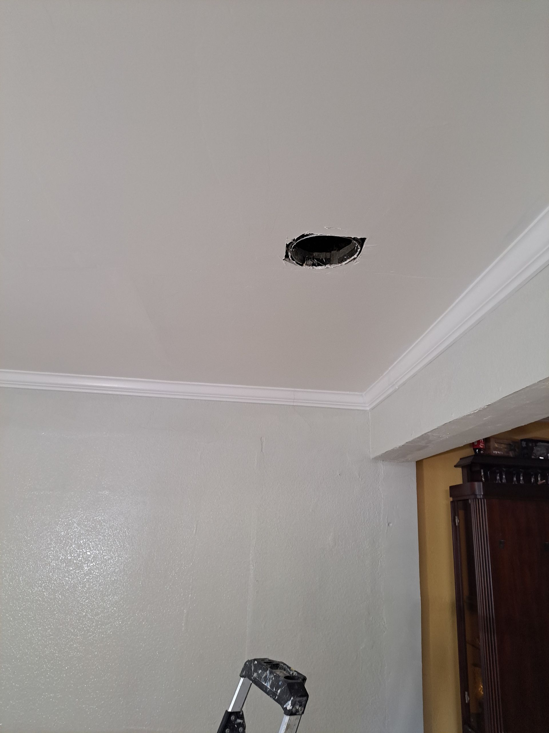 A room with a hole in the ceiling and a ladder.