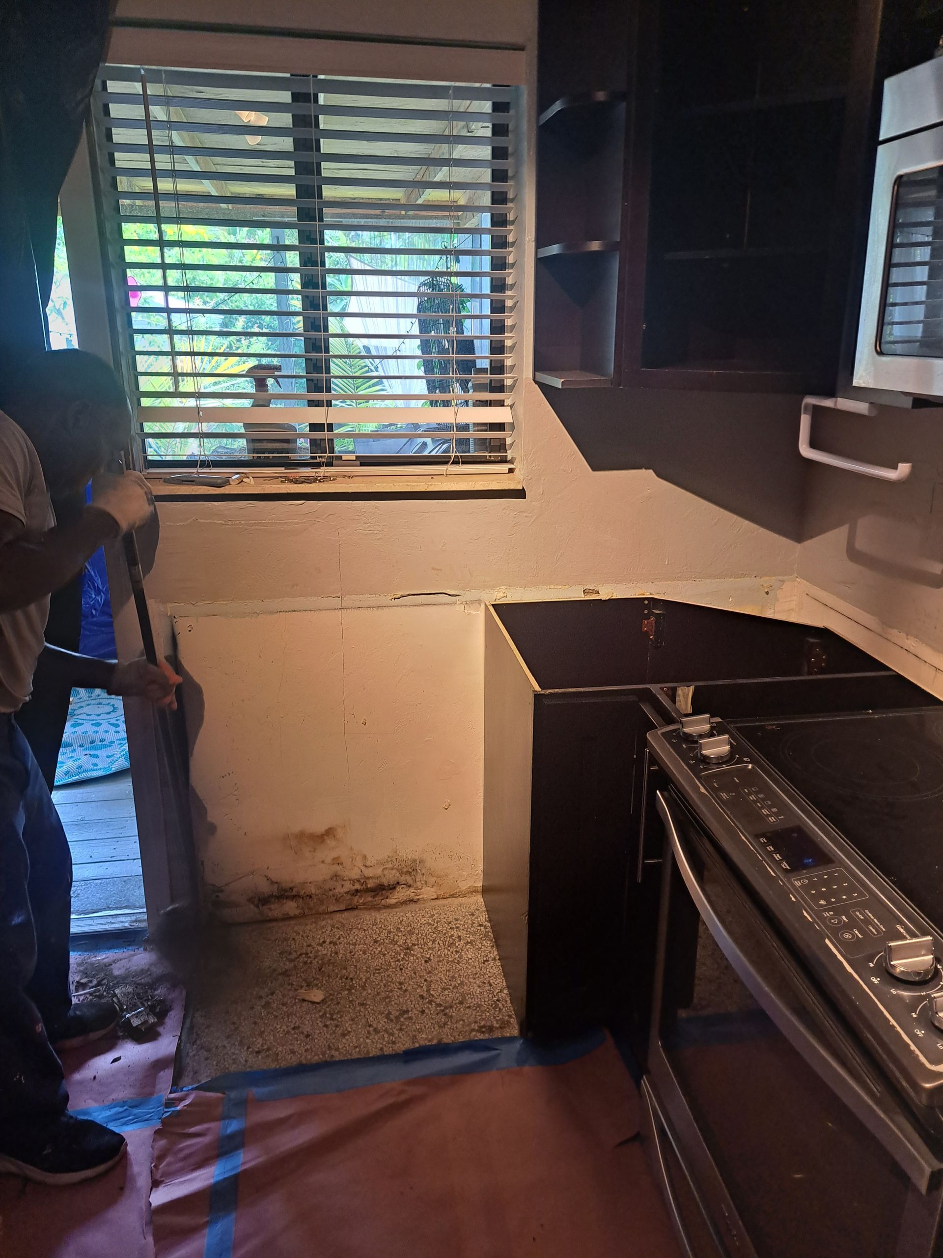 A man is cleaning a kitchen with a mop.