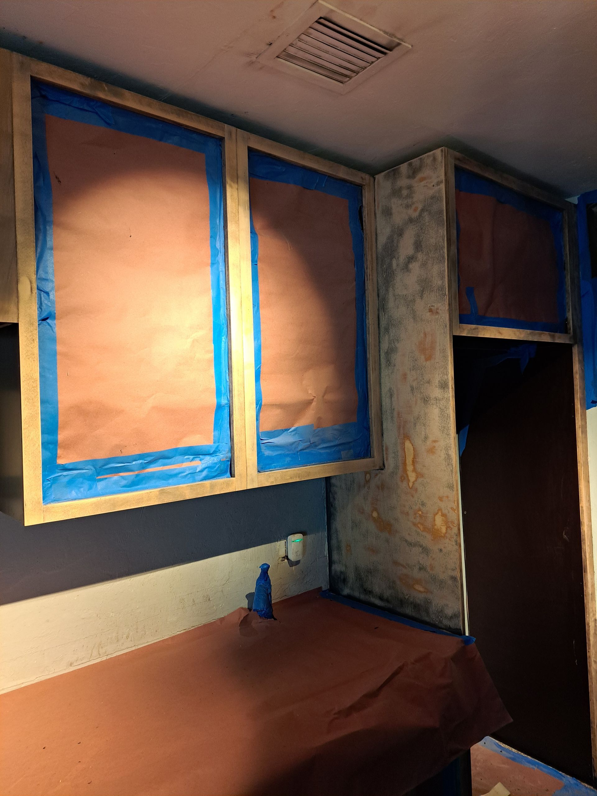 A room with brown cabinets and blue tape on them