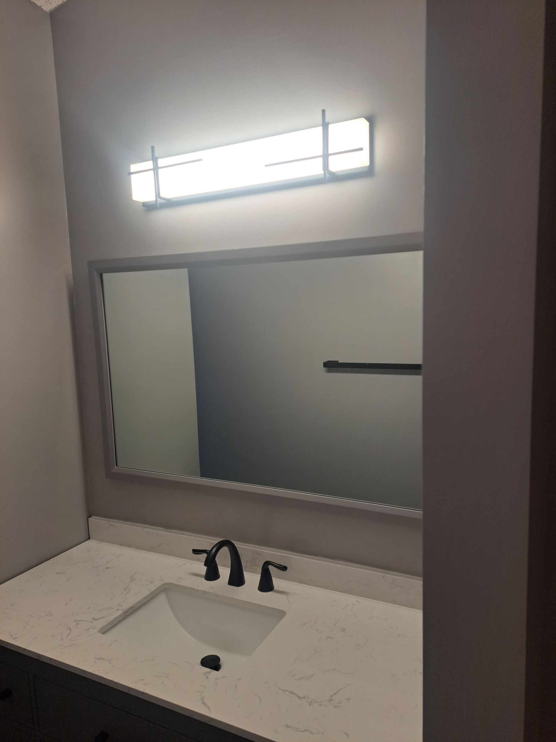 A bathroom with a sink , mirror and light.