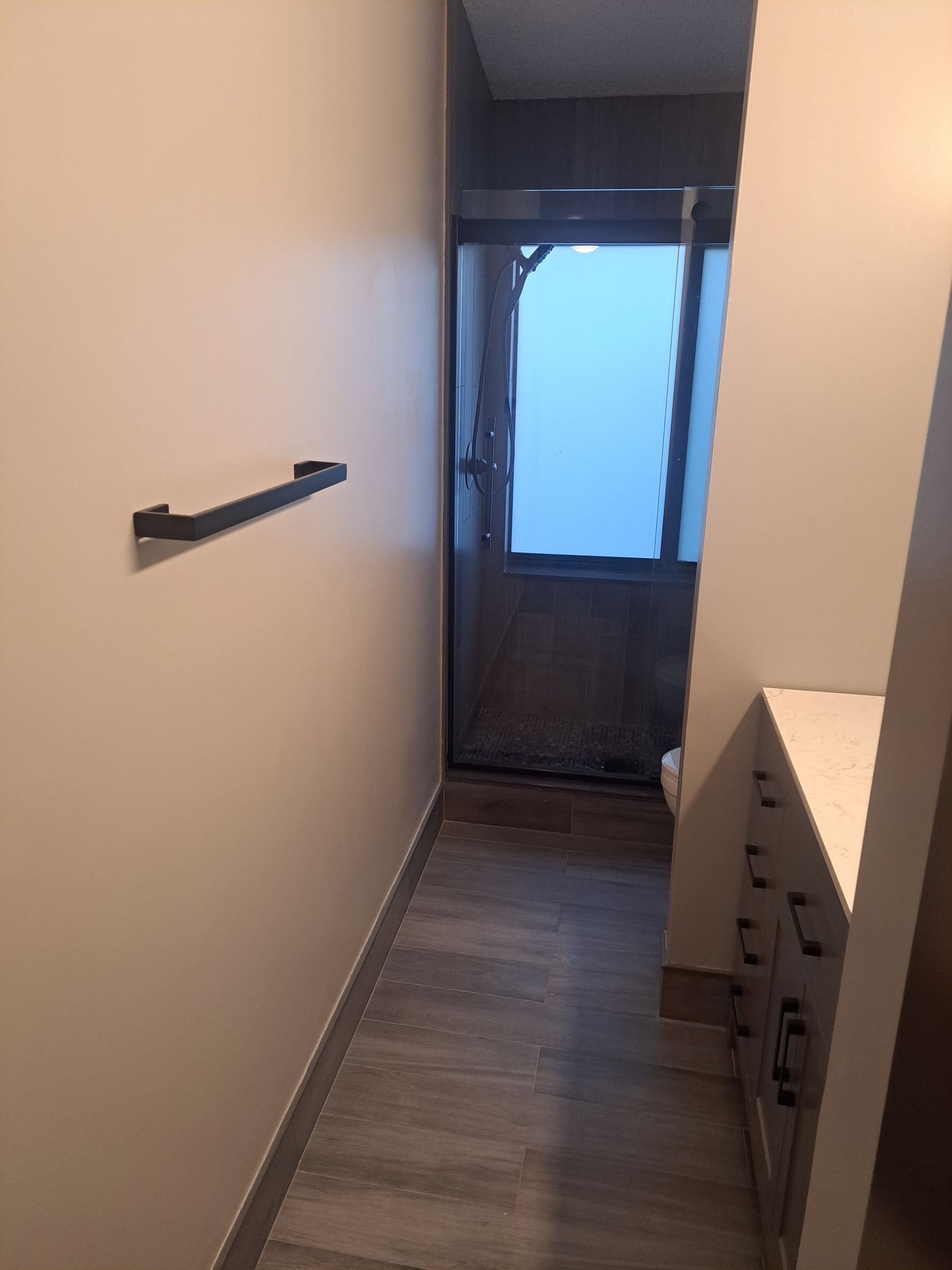A bathroom with a walk in shower and a towel rack.