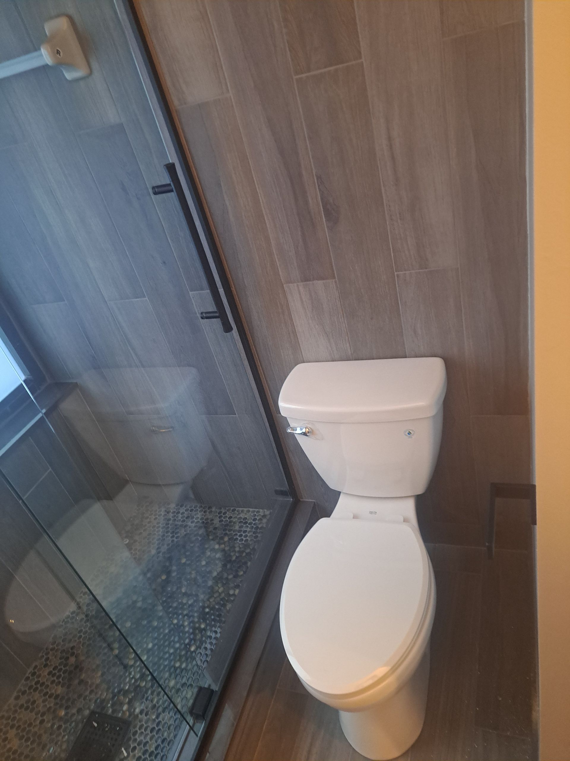 A toilet is sitting in a bathroom next to a shower stall.