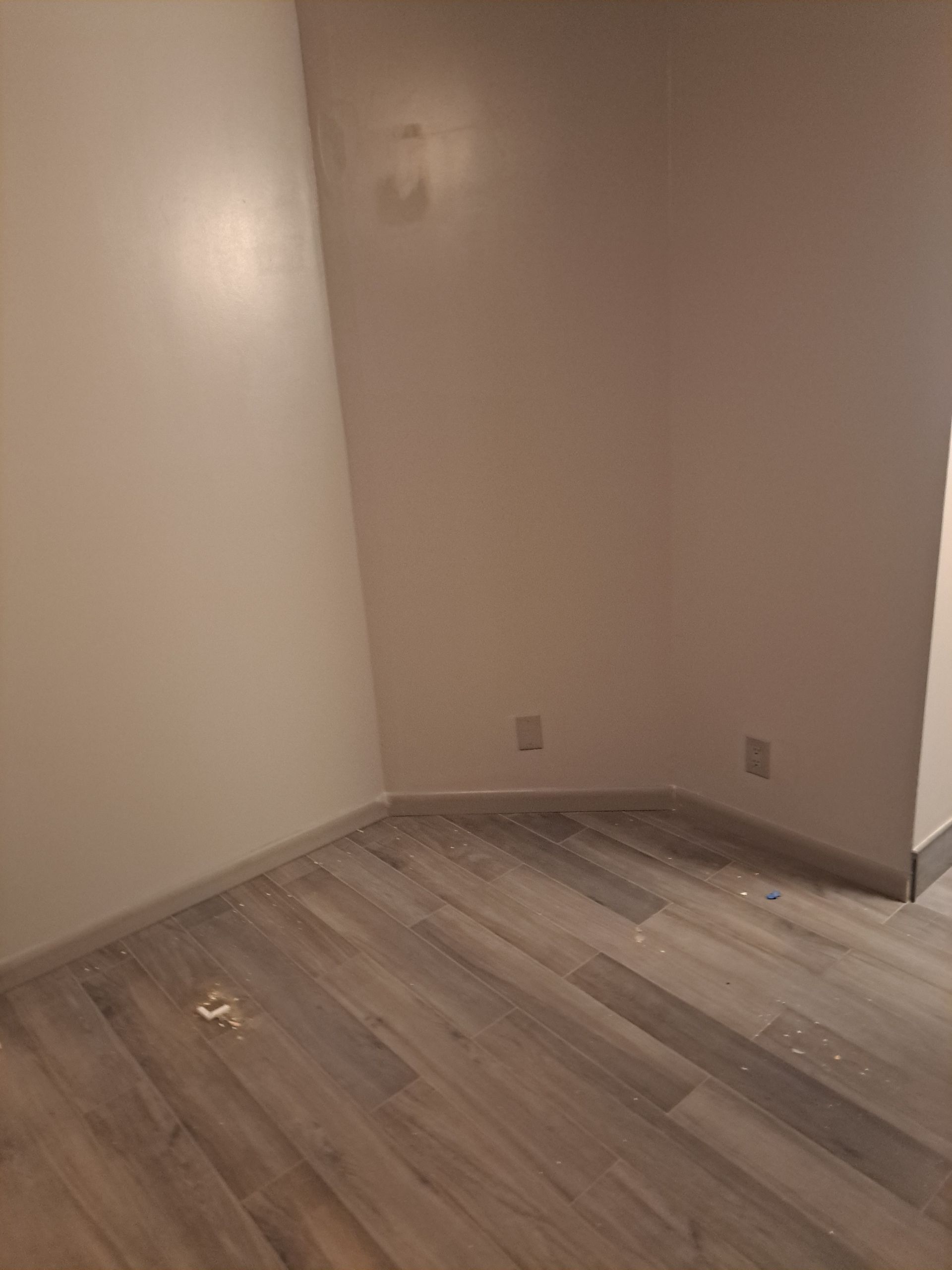 An empty room with a wooden floor and white walls.