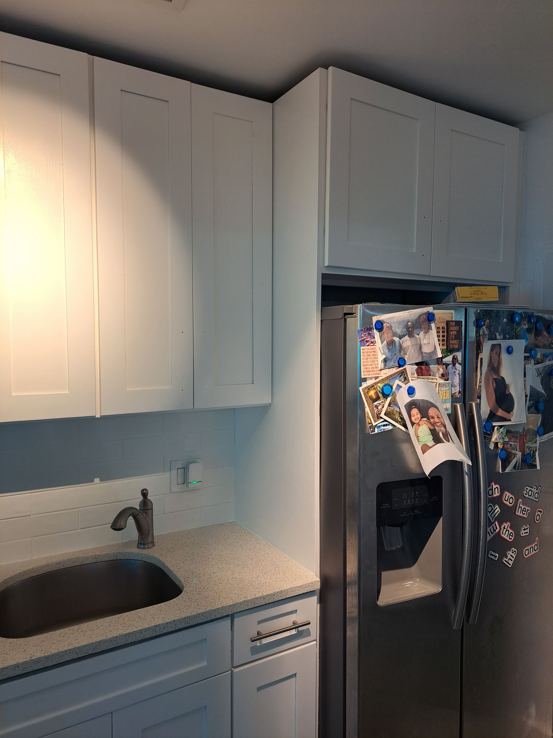 A kitchen with white cabinets and a stainless steel refrigerator