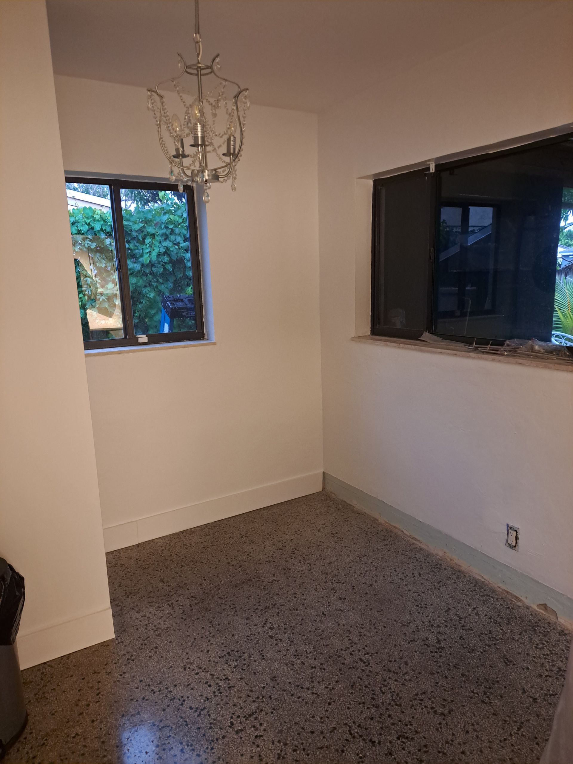 An empty room with a chandelier hanging from the ceiling and a window.