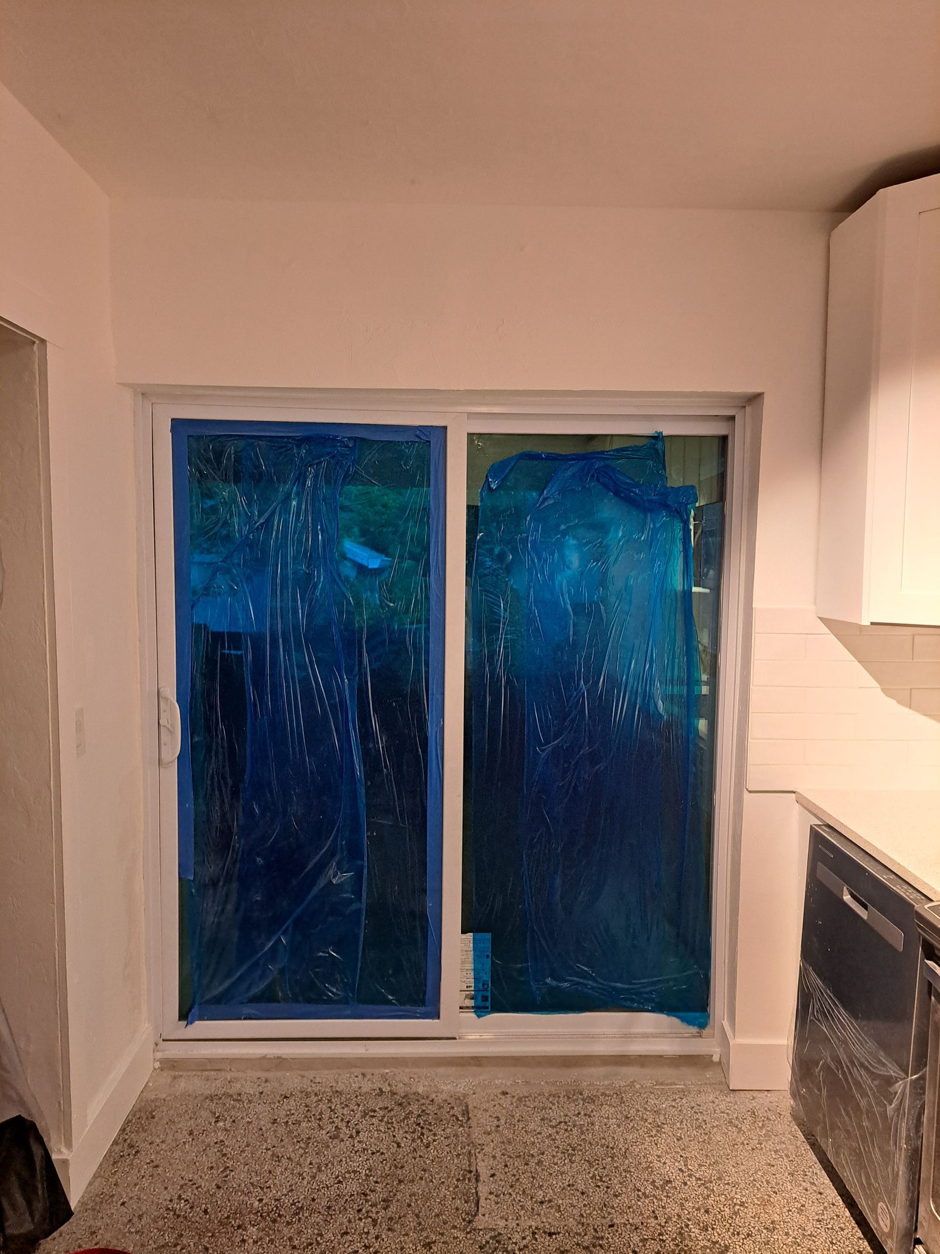 A sliding glass door is being installed in a kitchen.